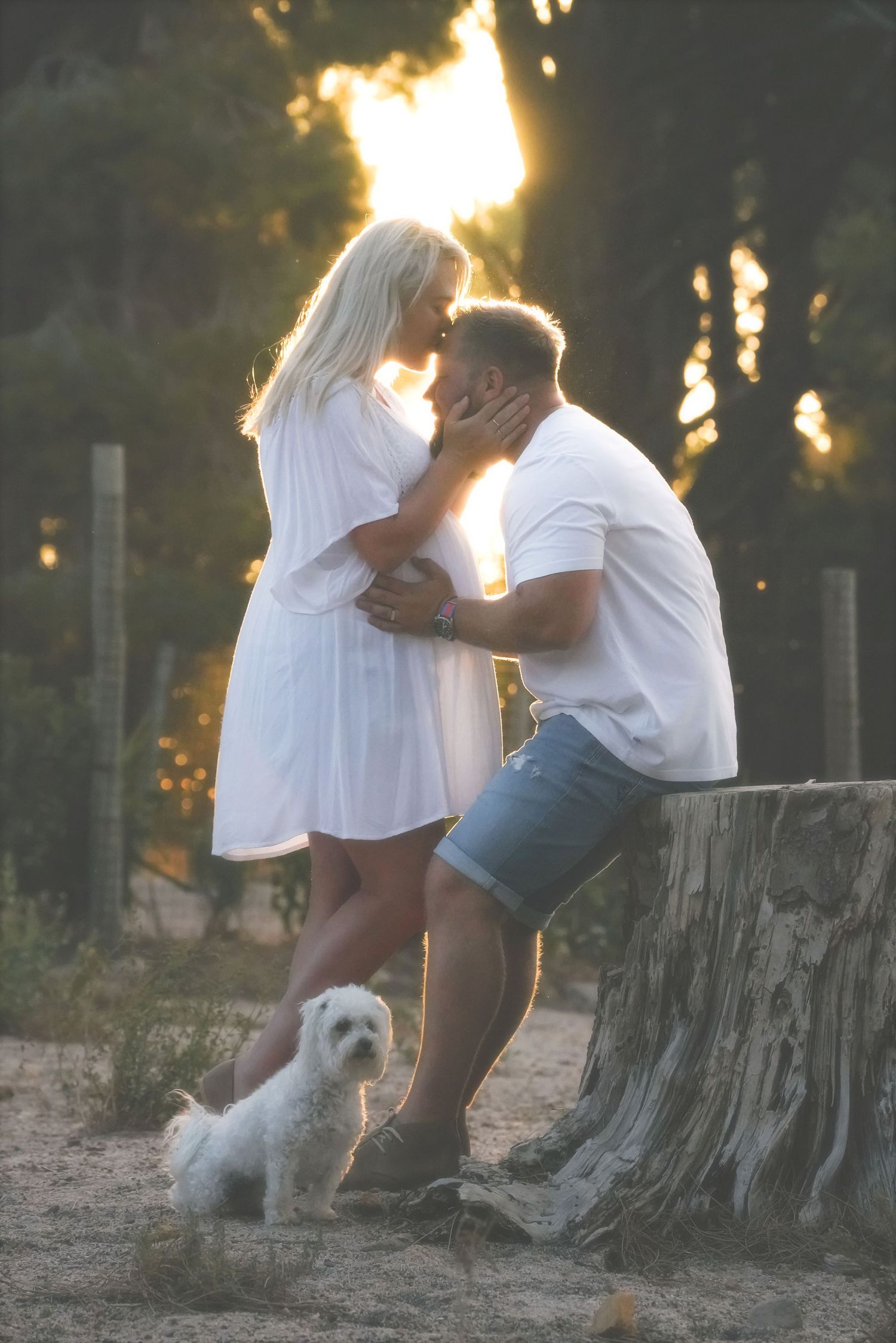 Couple holding each other close with the sun flaring behind them