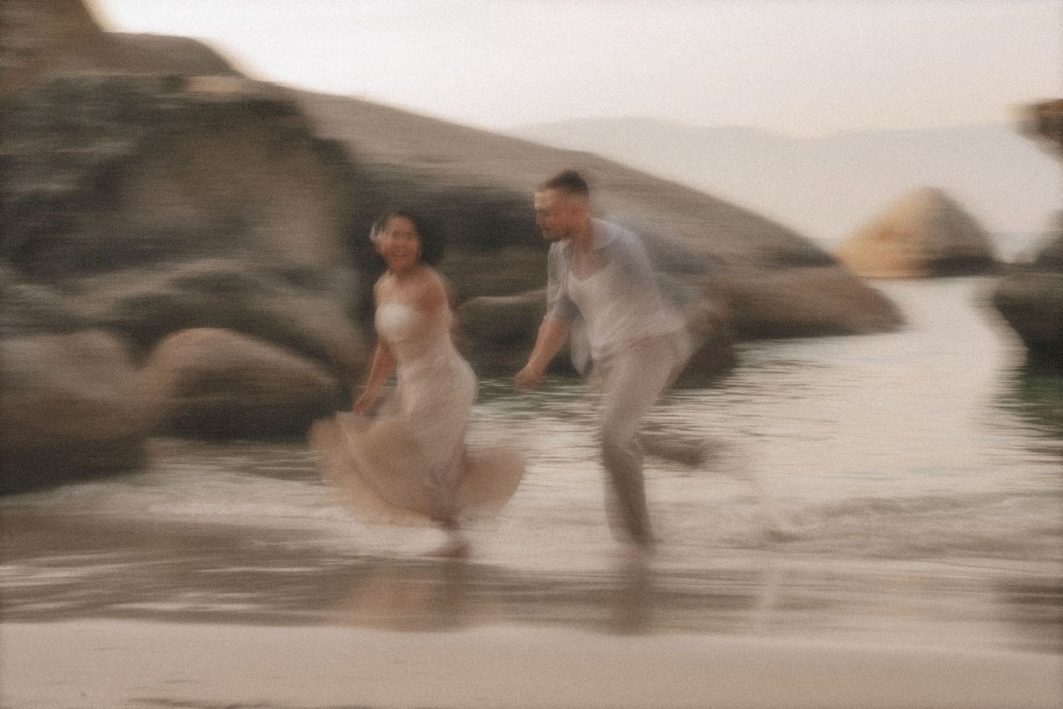 Couple running and playing through shallow water in soft motion blur