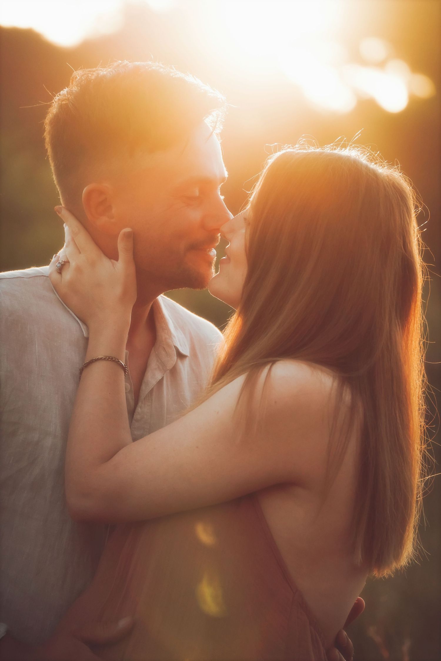 Close-up of a couple embracing nose to nose, glowing in the setting sun