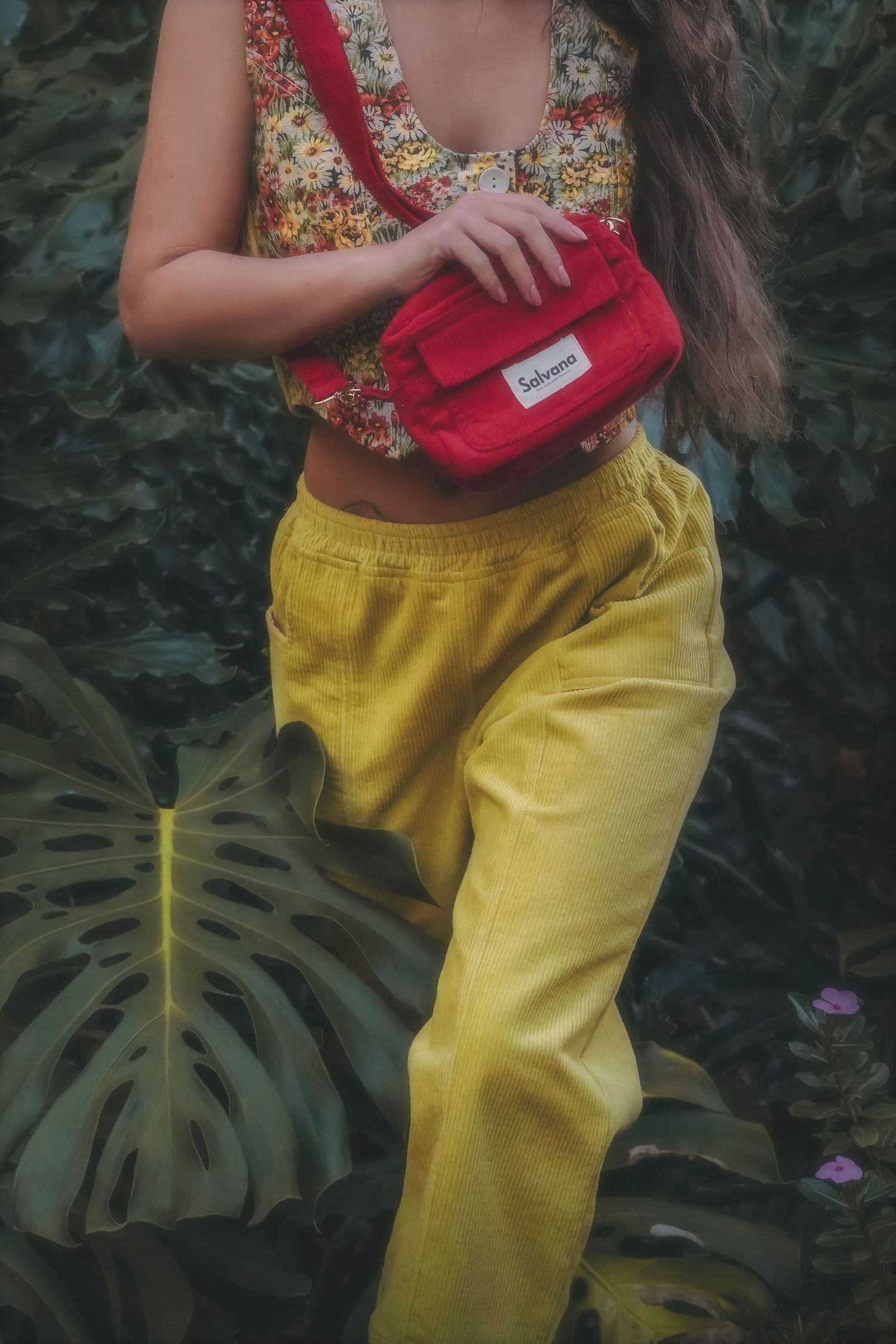 Close-up of a red belt bag worn with a floral top and yellow trousers
