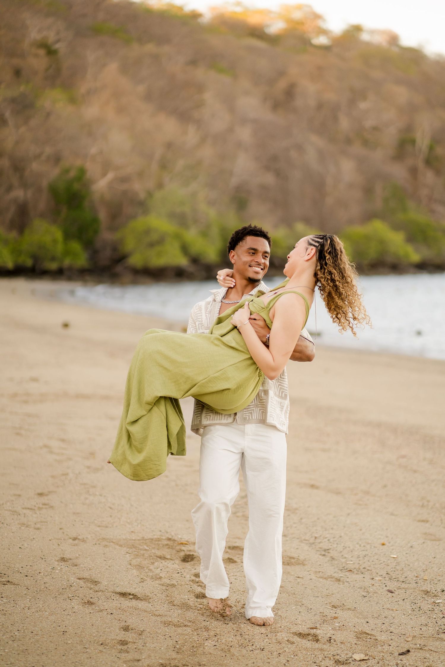 Engaged couple sharing a playful moment during their beach photography session at Andaz Costa Rica.