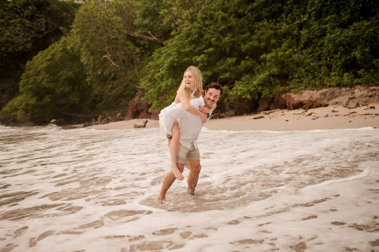 Couple playing in the ocean during a relaxed beach photography session at Playa Flamingo in Guanacaste, Costa Rica.