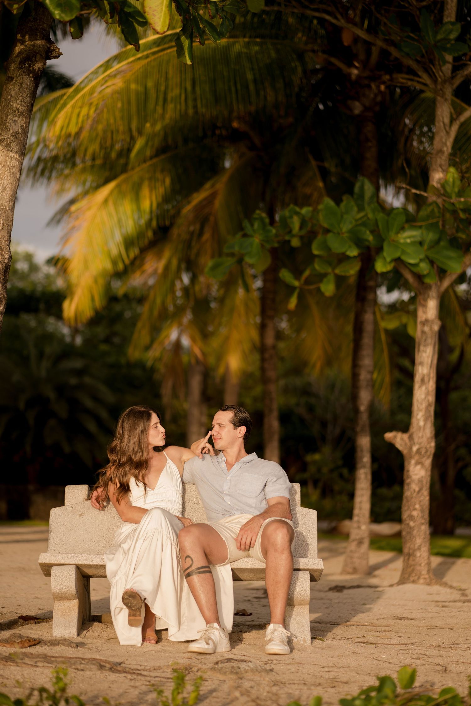 Couple sitting together beneath palm trees during a romantic photography session at Hacienda Pinilla in Guanacaste, Costa Rica.