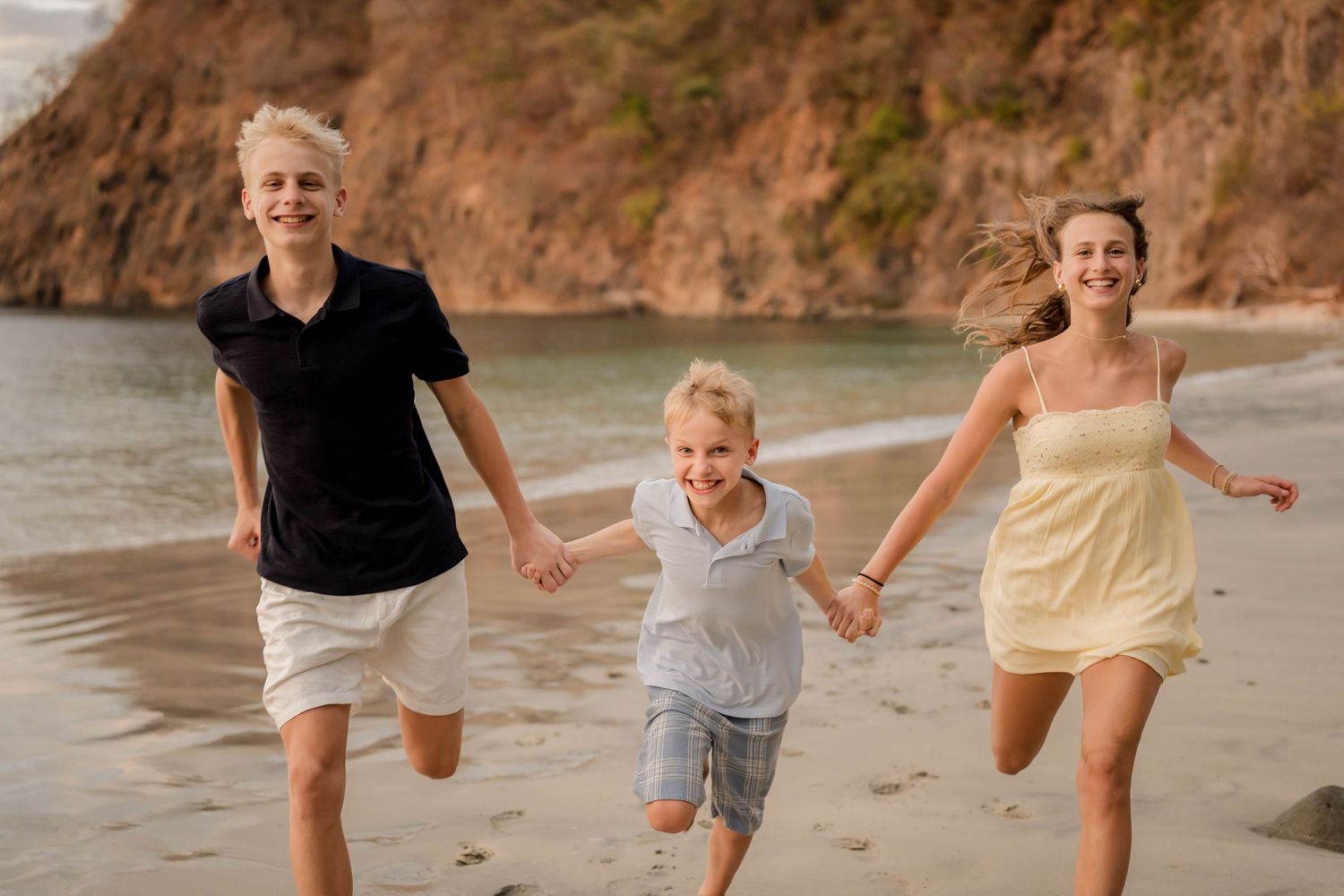 Children running together along the beach during a family photography session in Costa Rica.