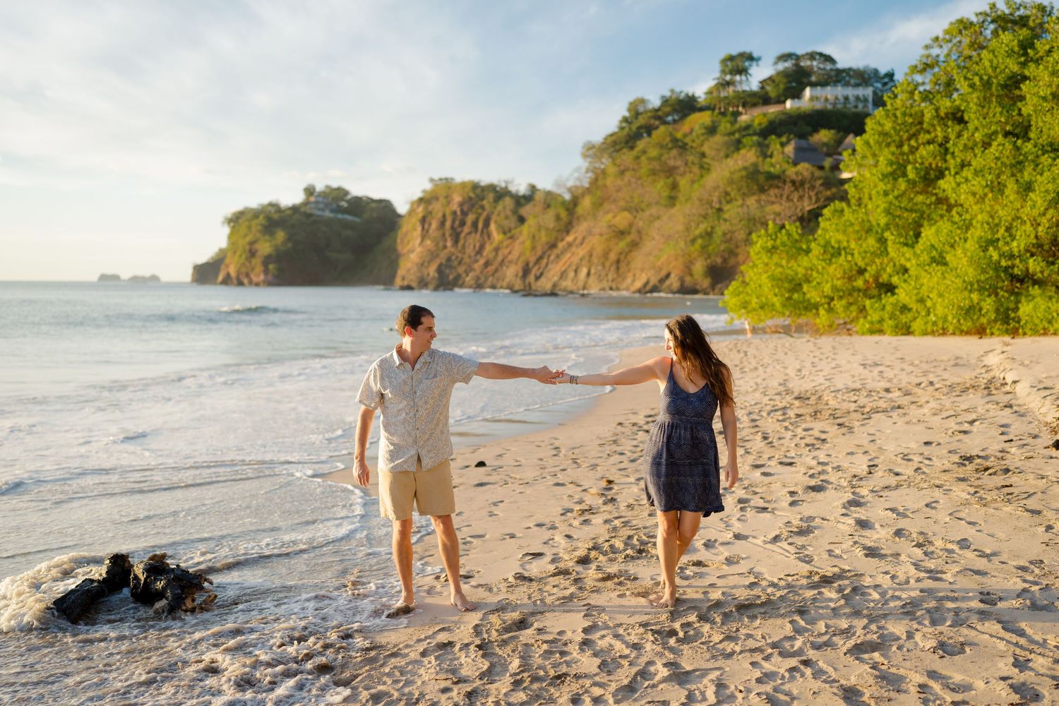 Couple walking and holding hands on a tropical beach during a golden hour vacation photography session in Costa Rica.