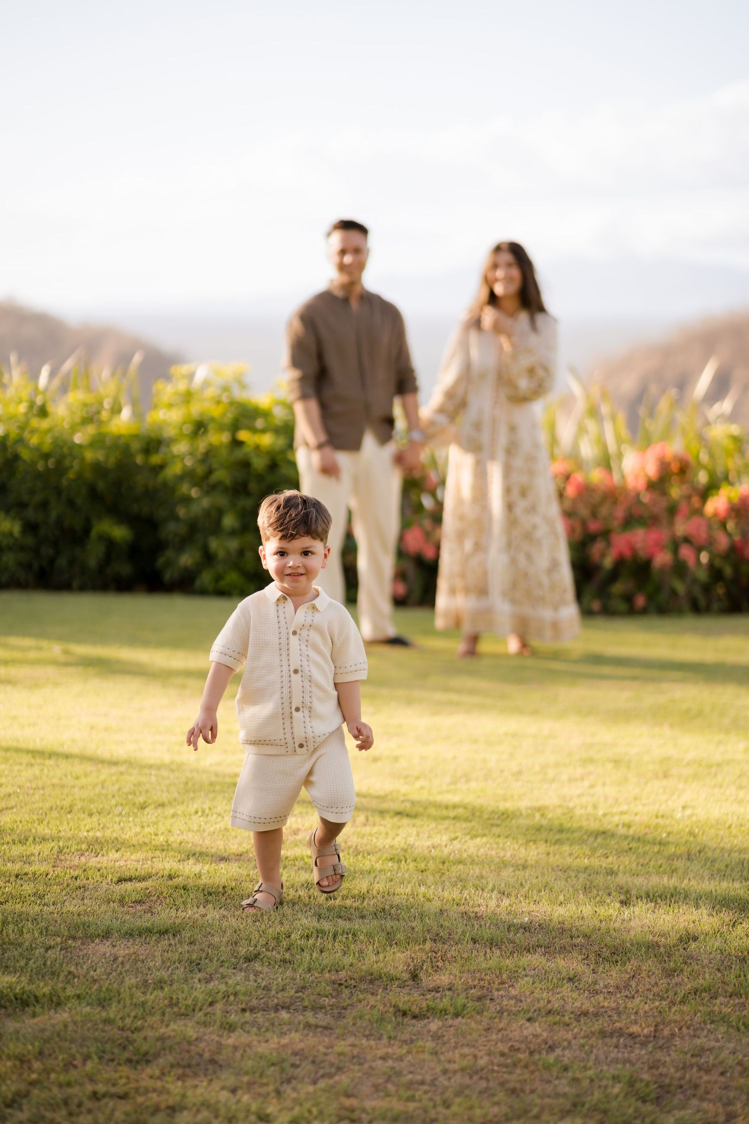 Young child running toward the camera with parents behind during a family photography session at Nekajui, a Ritz-Carlton Reserve in Costa Ri
