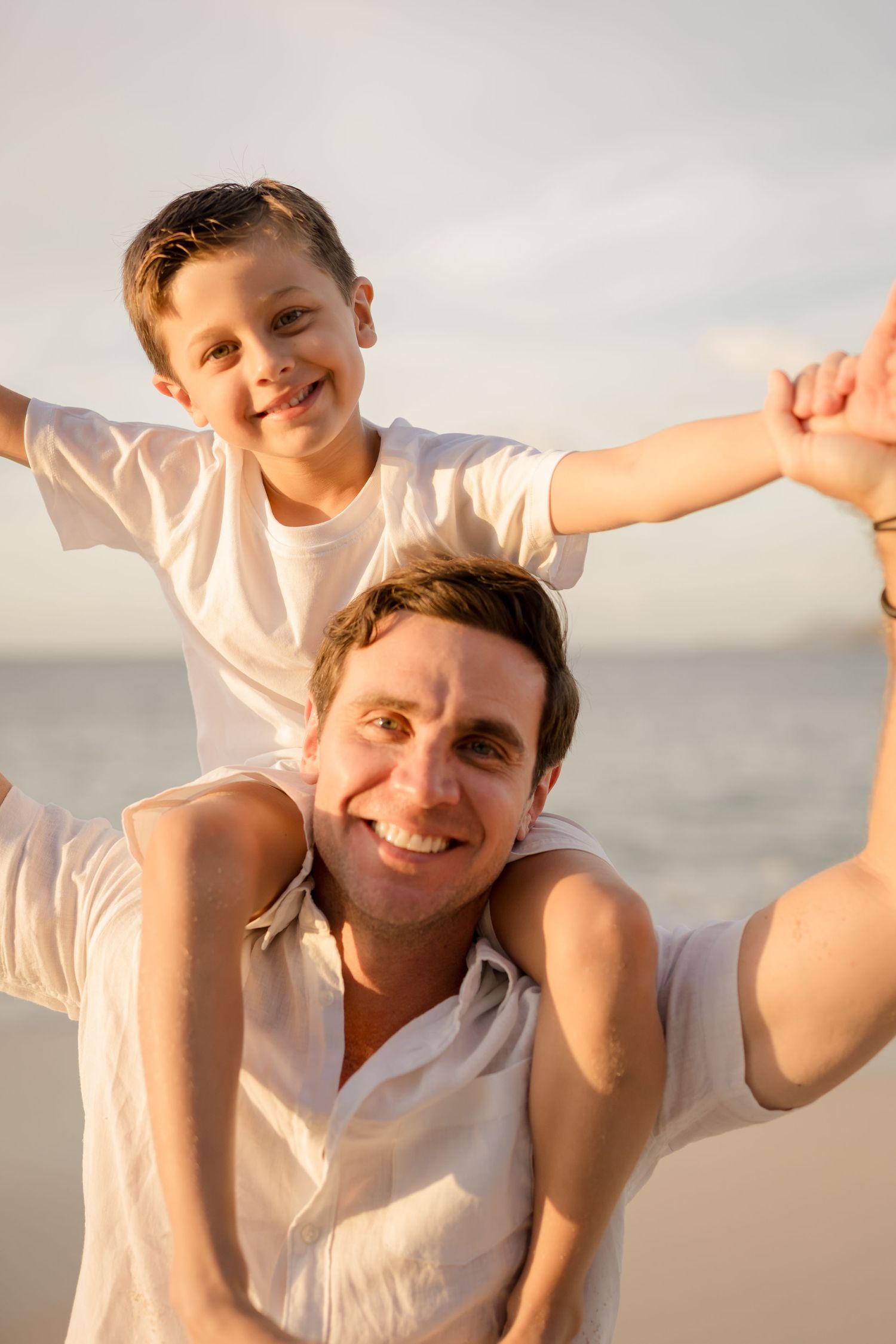 Father and son playing together by the ocean during a sunset family session at Playa Conchal.