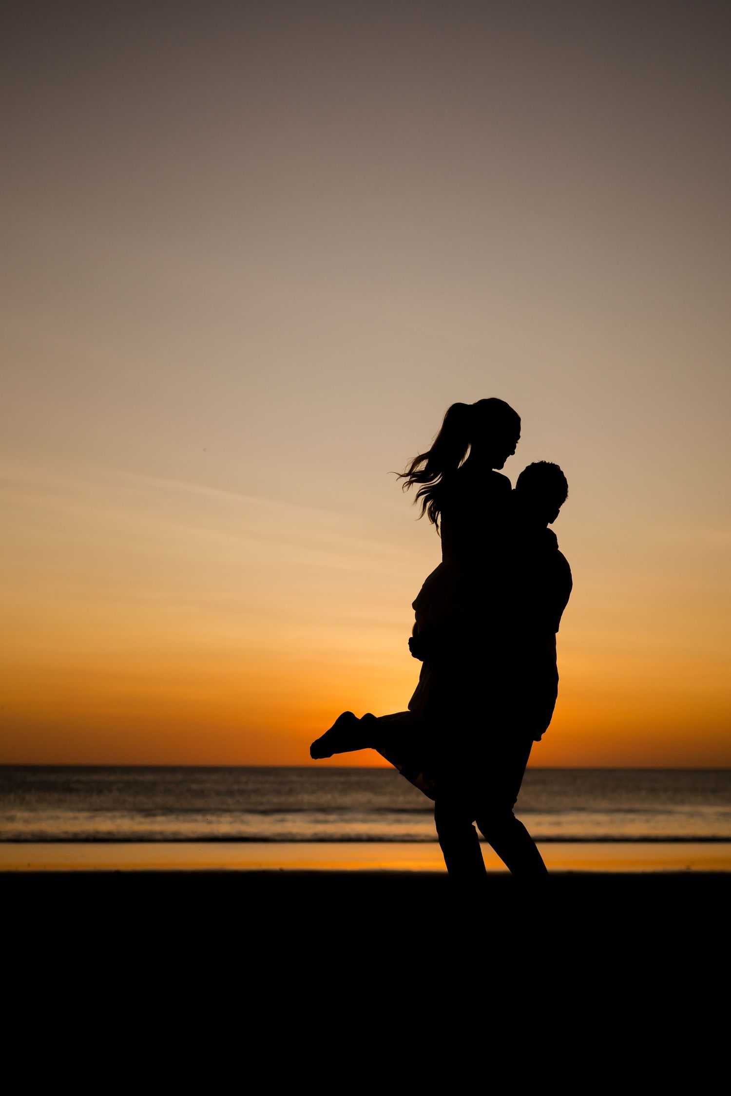 Couple embracing in silhouette at sunset during a romantic beach photography session at Hacienda Pinilla, Costa Rica.
