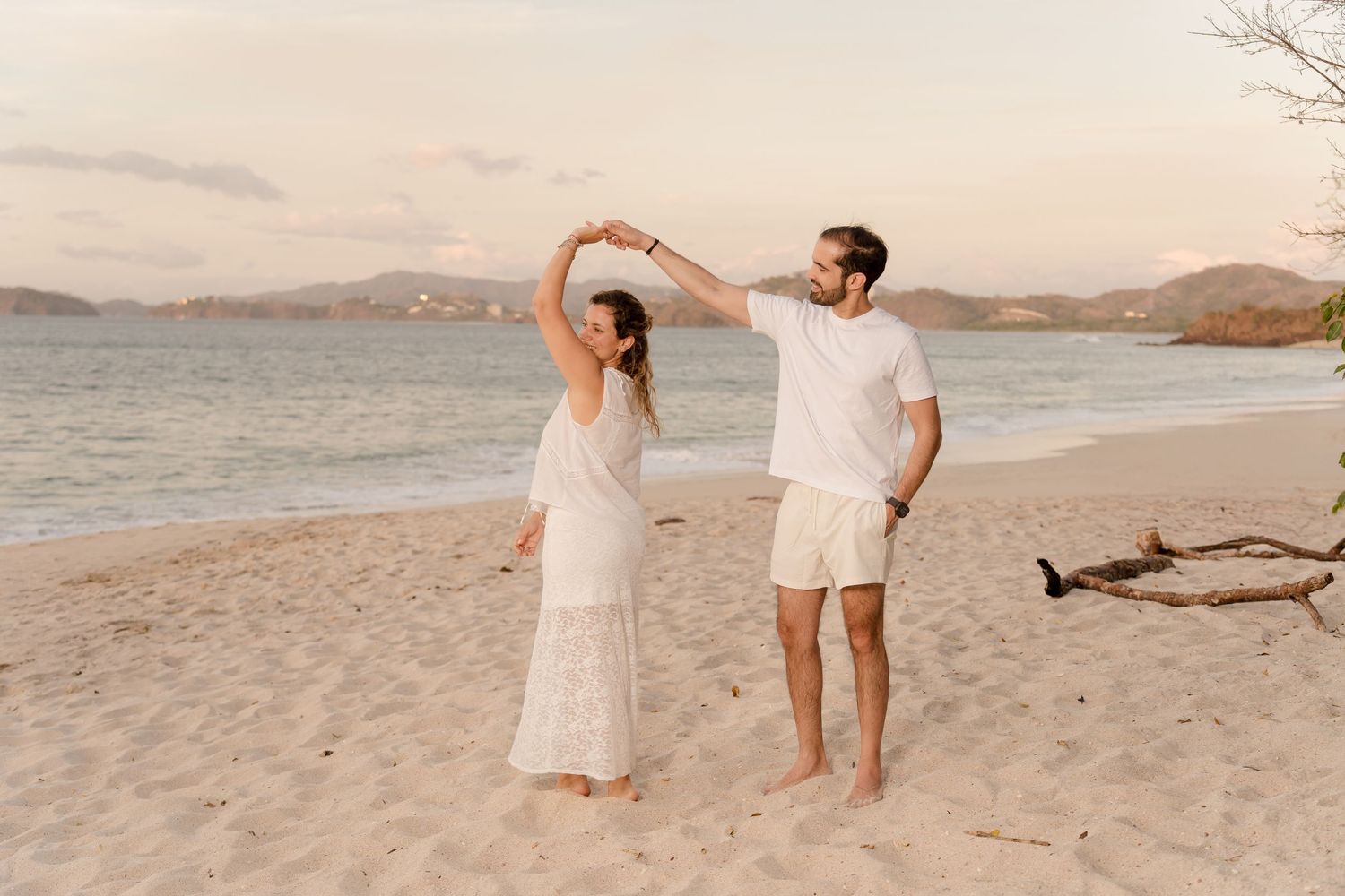 Parents dancing together along the shoreline during a sunset family session at Playa Conchal.
