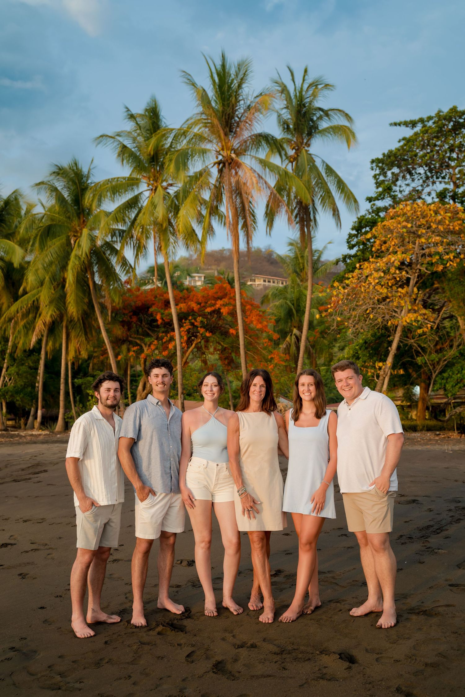 Family posing together beneath palm trees during a vacation photography session in Playas del Coco, Guanacaste, Costa Rica.
