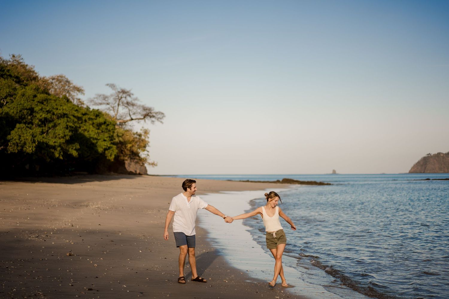 Family enjoying a playful moment by the ocean during a beach photography session in Costa Rica.
