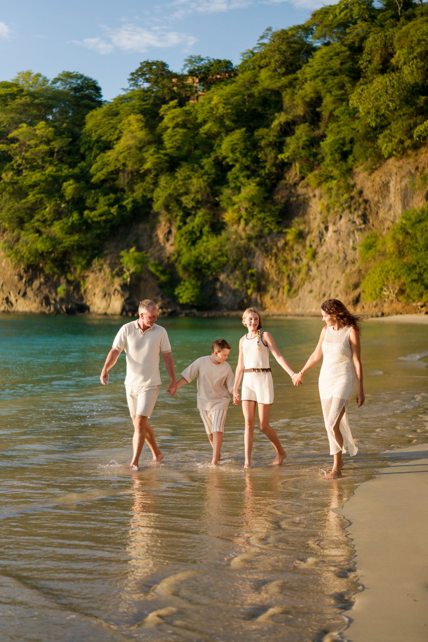 Family of four walking together through the ocean during a beach photography session at Four Seasons Costa Rica at Peninsula Papagayo.