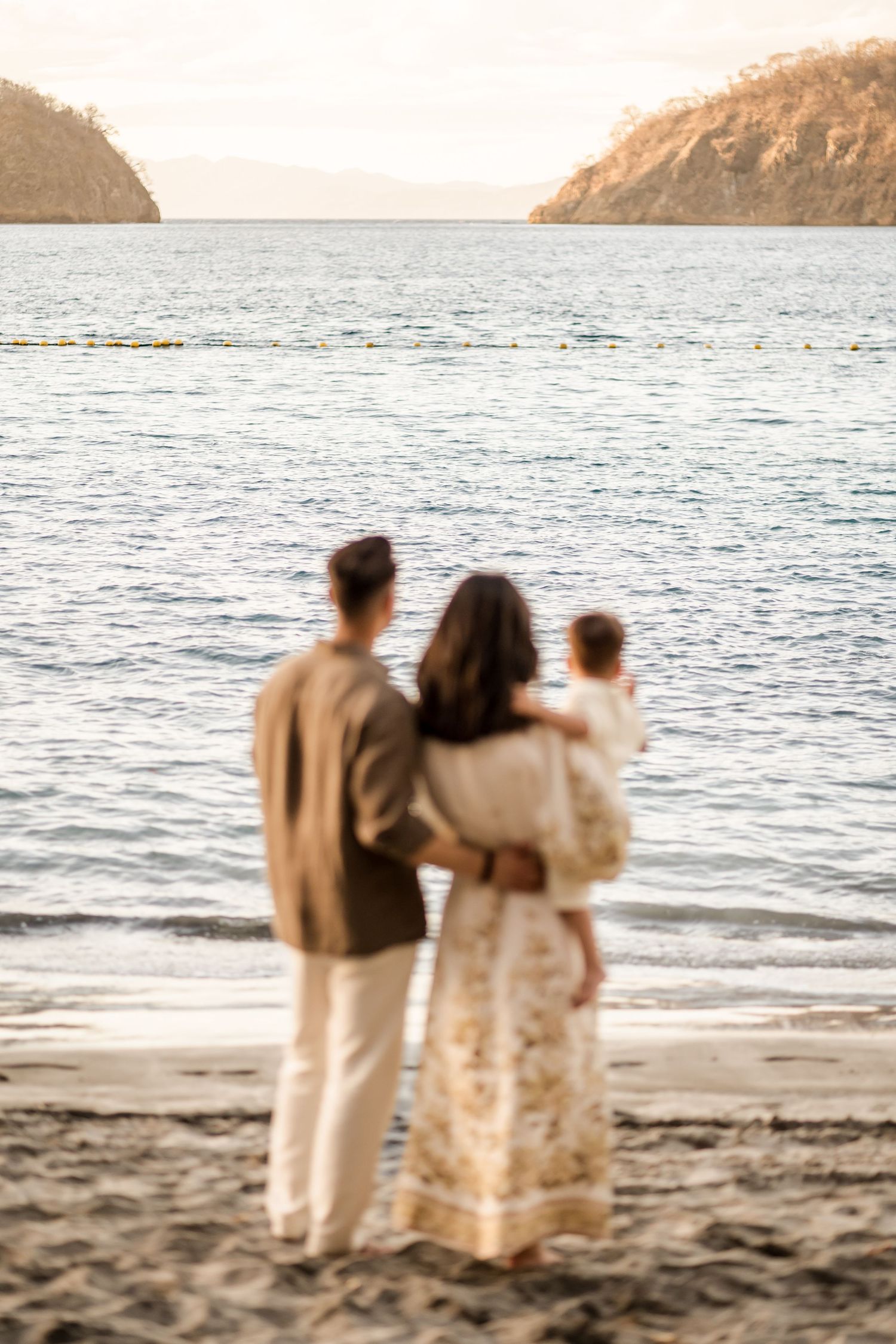 Family embracing by the ocean during a sunset photography session at Nekajui, a Ritz-Carlton Reserve in Costa Rica.