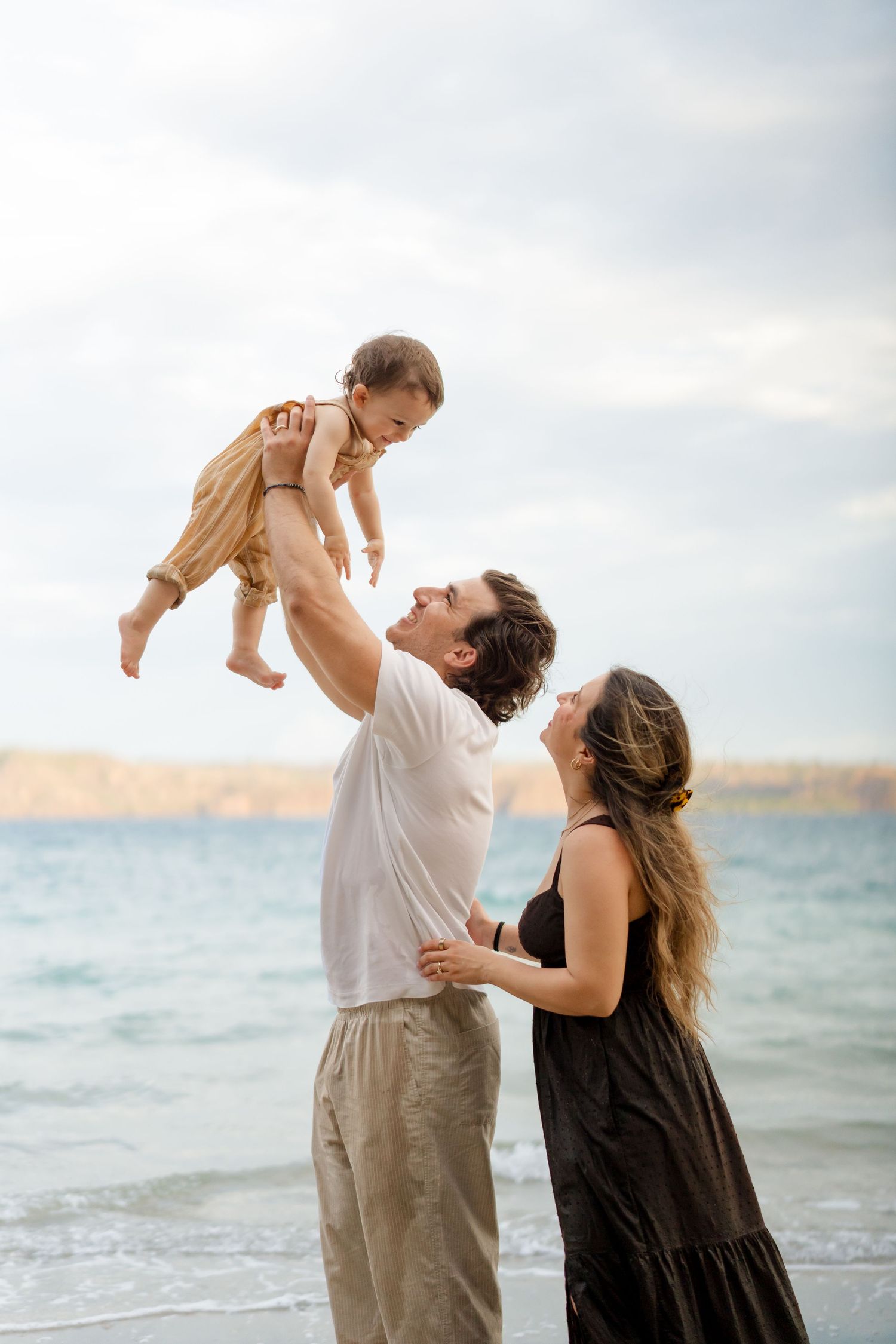 Parents playing with their young child on the beach during a family vacation session at Andaz Peninsula Papagayo, Costa Rica.