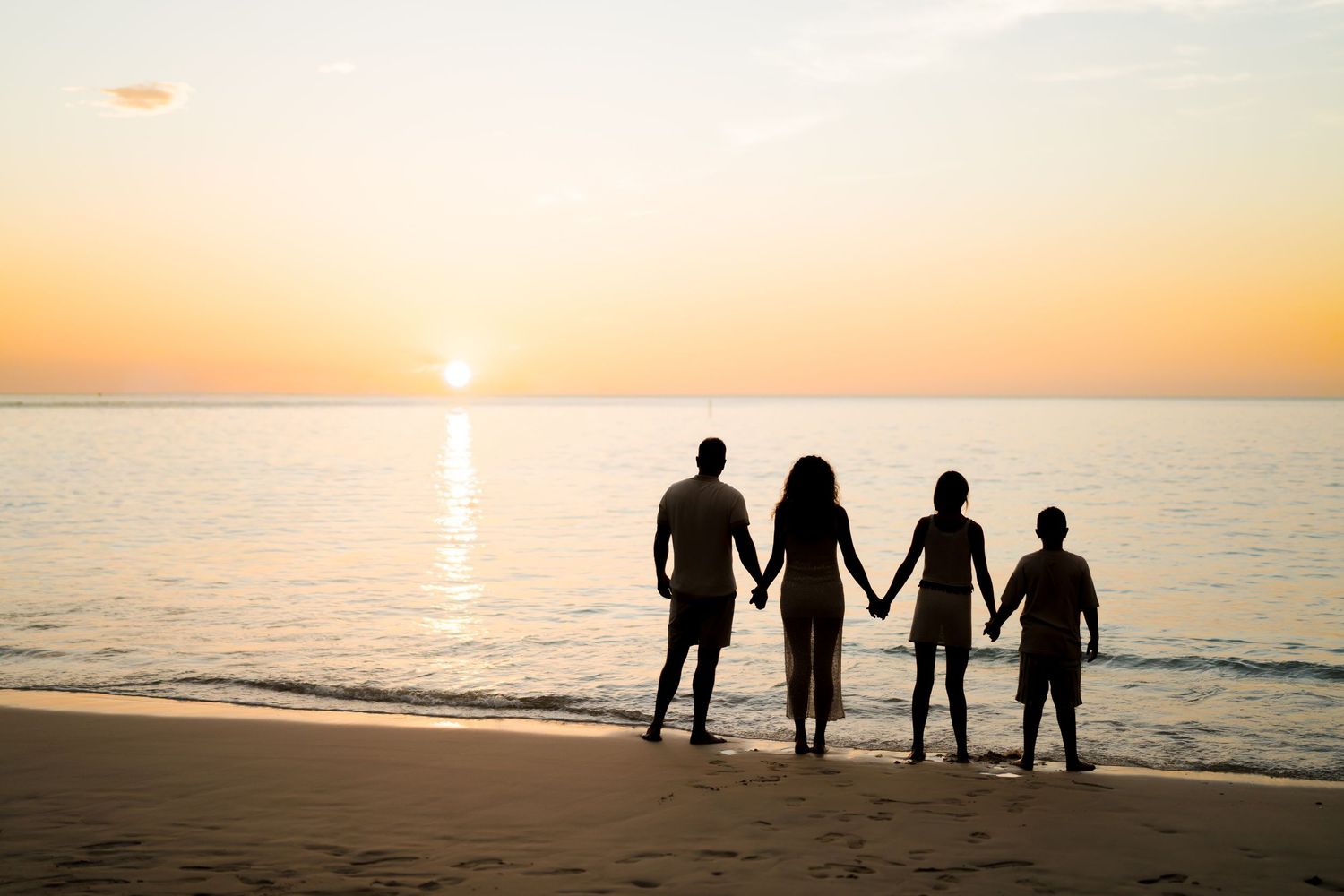 Family of four holding hands on the beach at sunset during a family photography session in Guanacaste, Costa Rica.