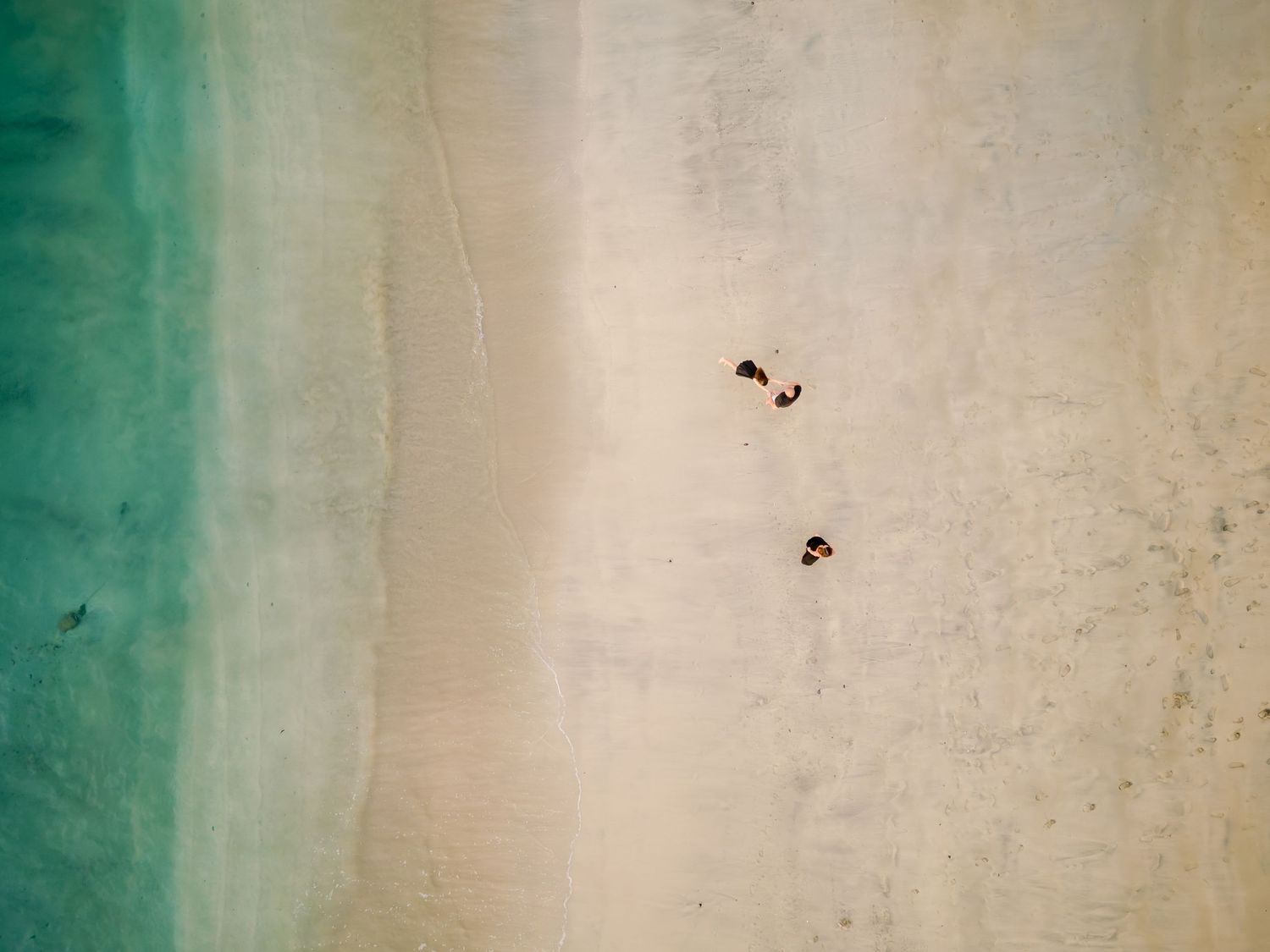 Aerial view of a family on a tropical beach with turquoise water at Four Seasons Peninsula Papagayo, Costa Rica.