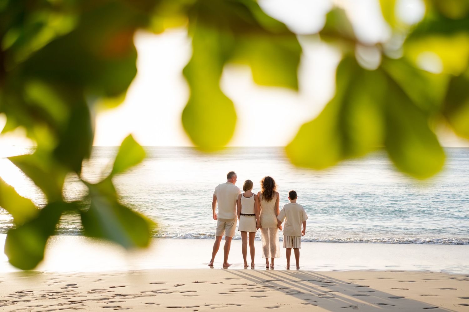 Parents and their two children standing together on the beach during a family photography session at Four Seasons Costa Rica at Peninsula Pa