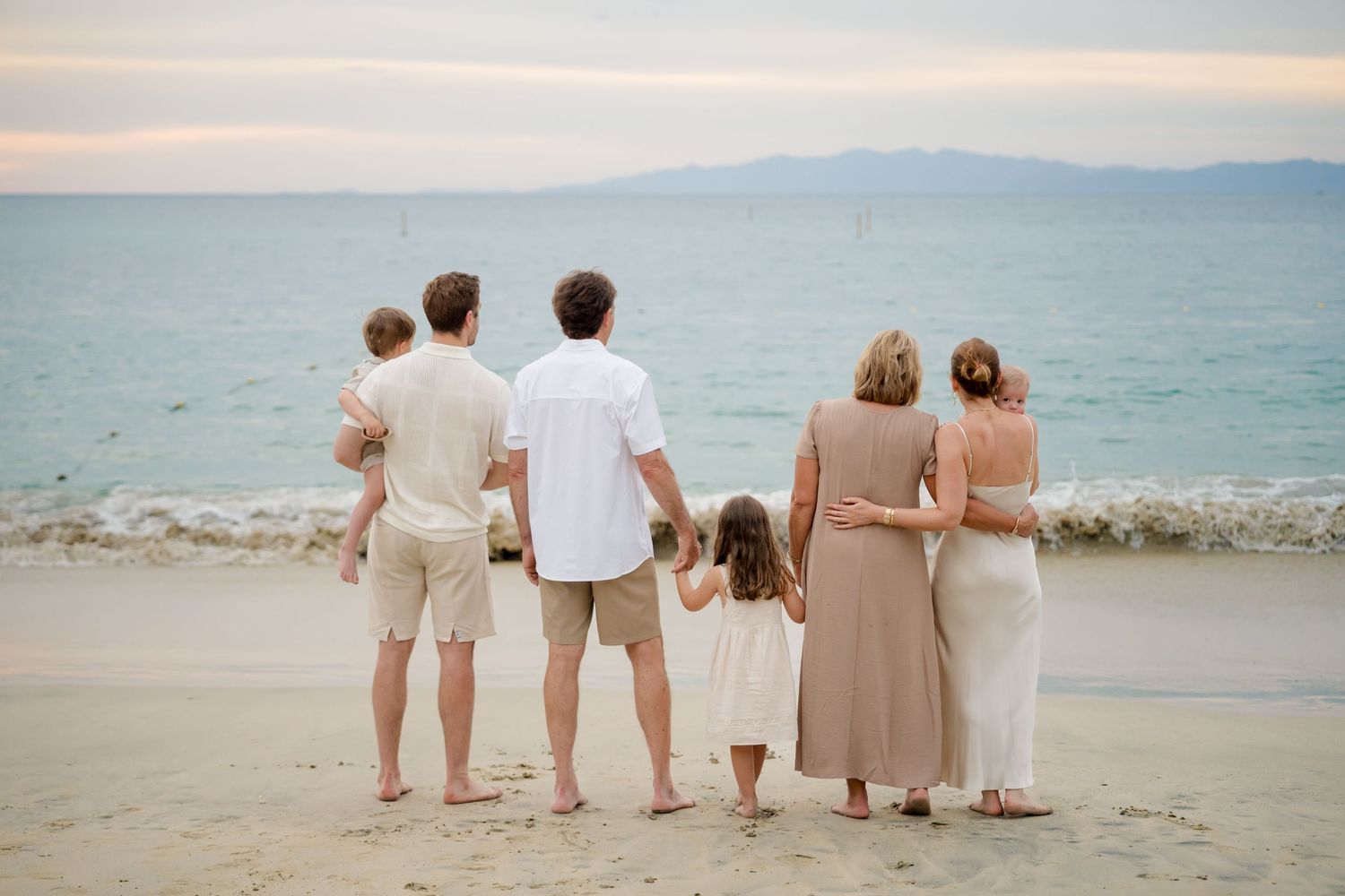 Family dressed in neutral tones looking toward the ocean during a beach photography session at Four Seasons Costa Rica at Peninsula Papagayo
