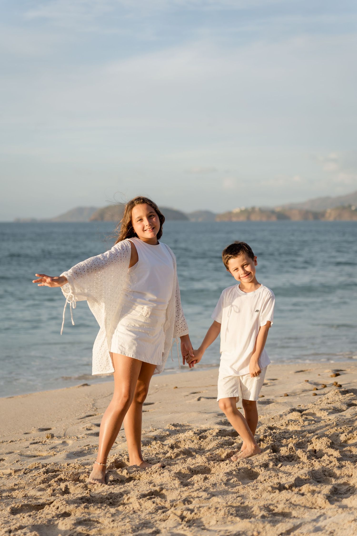 siblings walking hand in hand along Playa Conchal during their Costa Rica family vacation.