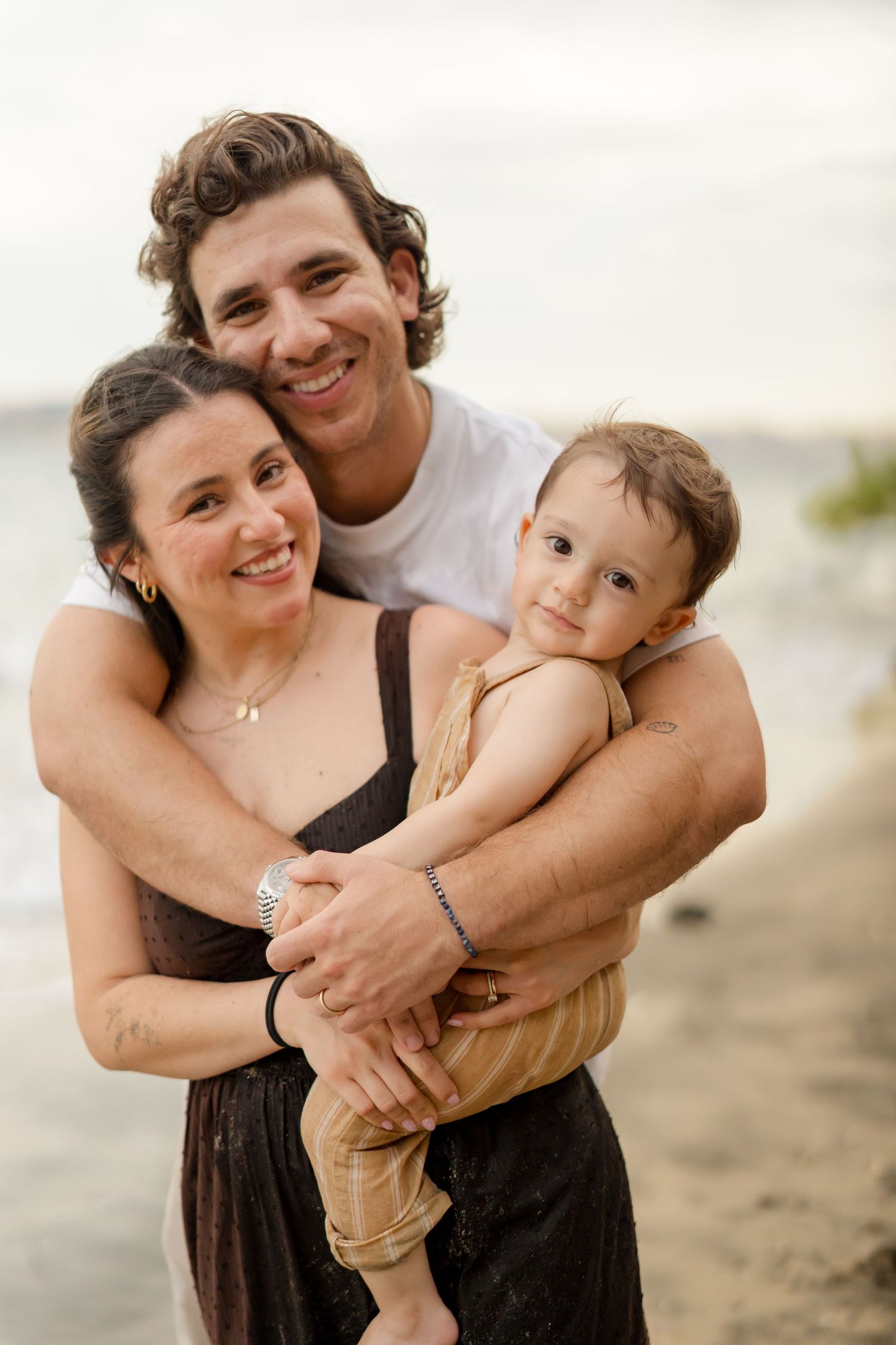 Parents embracing their young child during a relaxed family photography session at Andaz Peninsula Papagayo, Costa Rica.