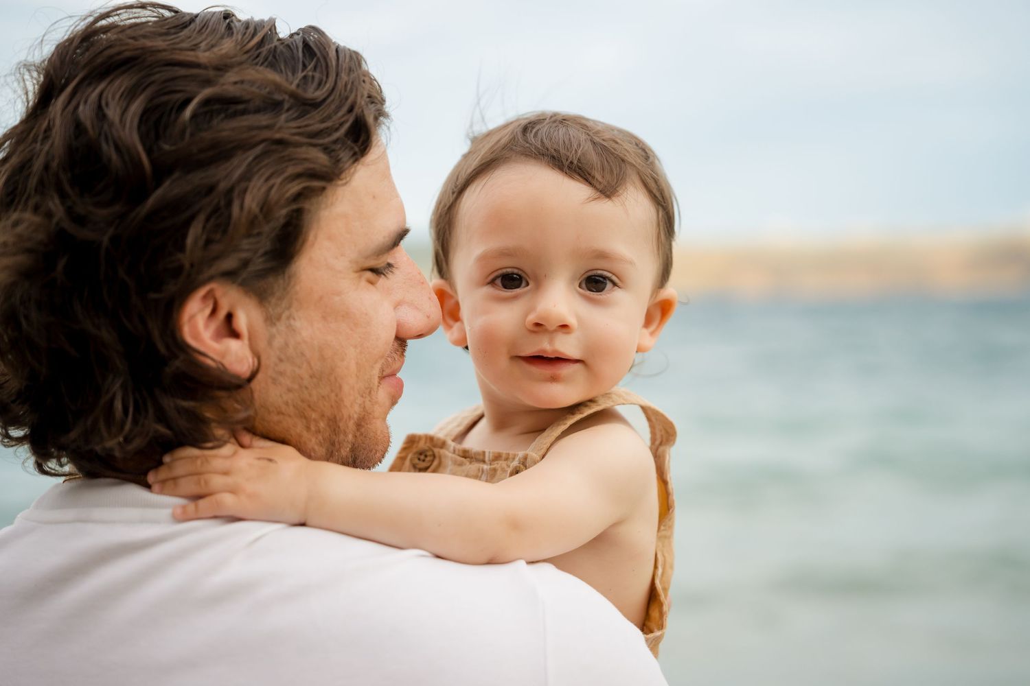 Father holding his young child by the ocean during a family photography session in Peninsula Papagayo, Costa Rica.