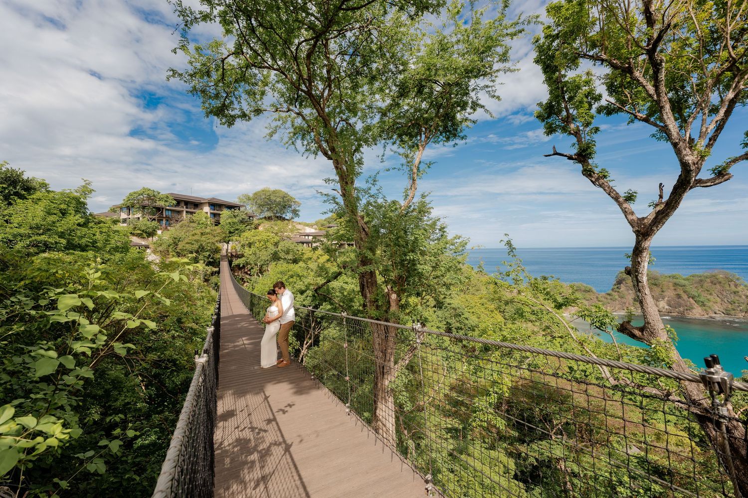 Couple walking across a suspension bridge surrounded by tropical scenery at Nekajui, a Ritz-Carlton Reserve in Costa Rica.