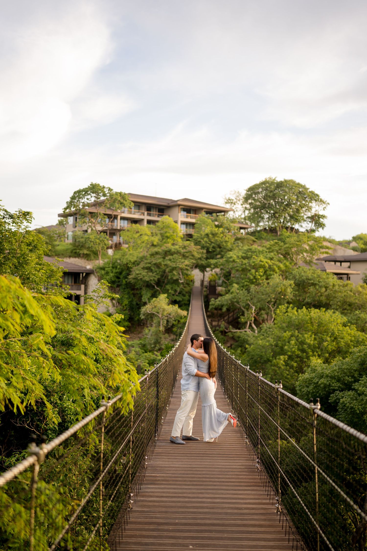 Couple walking across a suspension bridge during a romantic photography session at Nekajui, a Ritz-Carlton Reserve in Costa Rica.