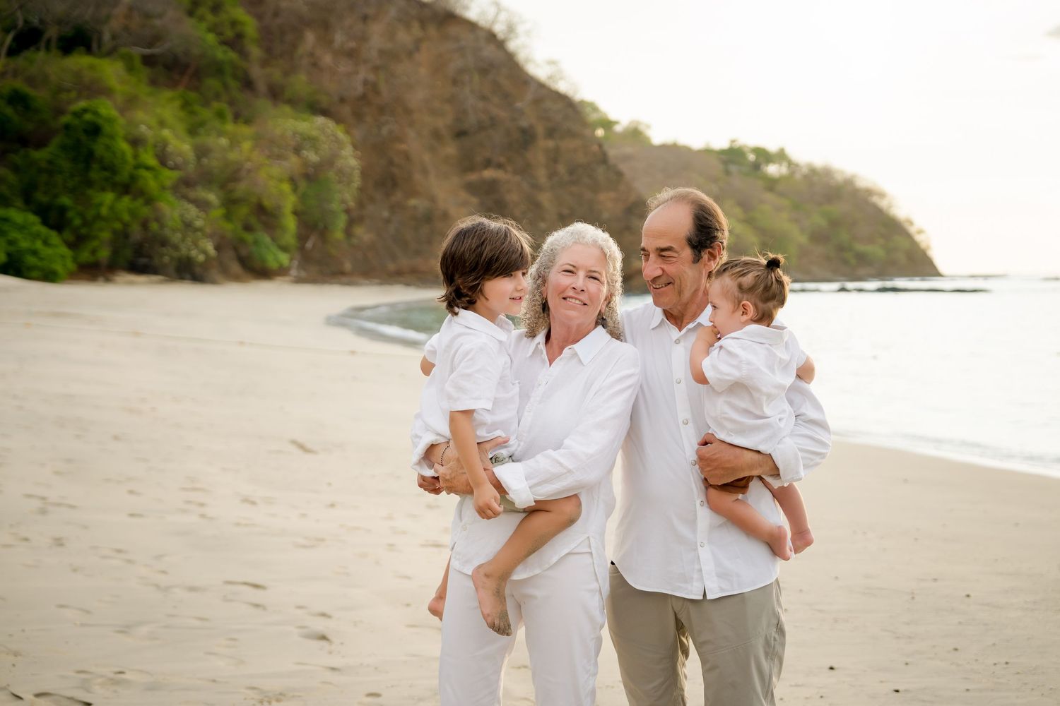 Grandparents holding their grandchildren during a family beach photography session at Four Seasons Peninsula Papagayo, Costa Rica.