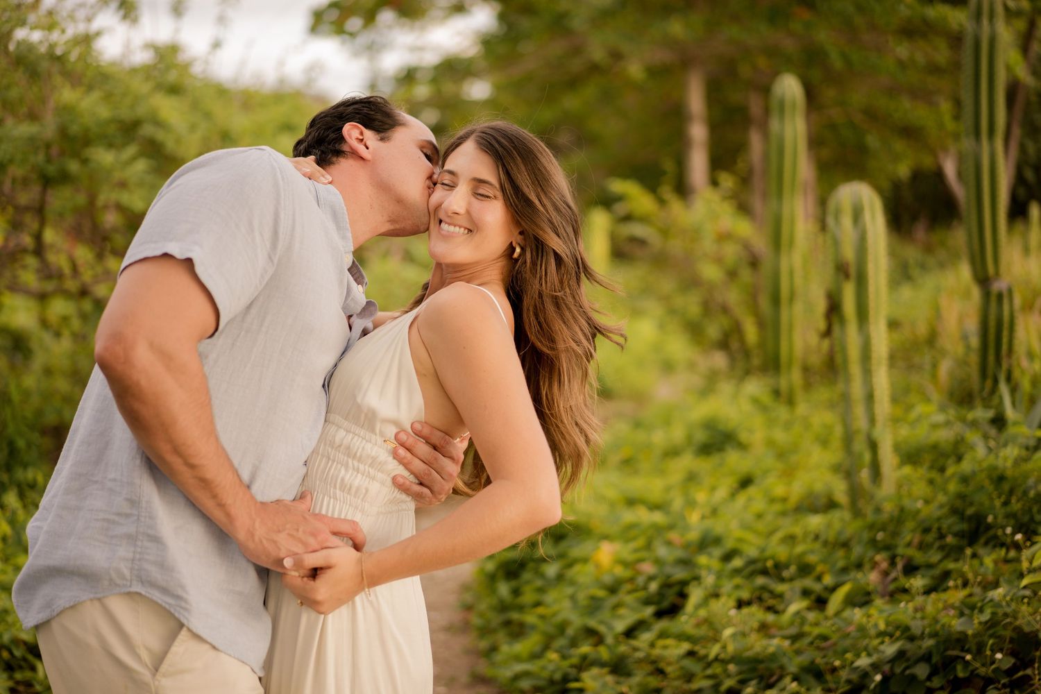 Couple sharing a playful moment surrounded by tropical scenery during a photography session at Hacienda Pinilla, Costa Rica.