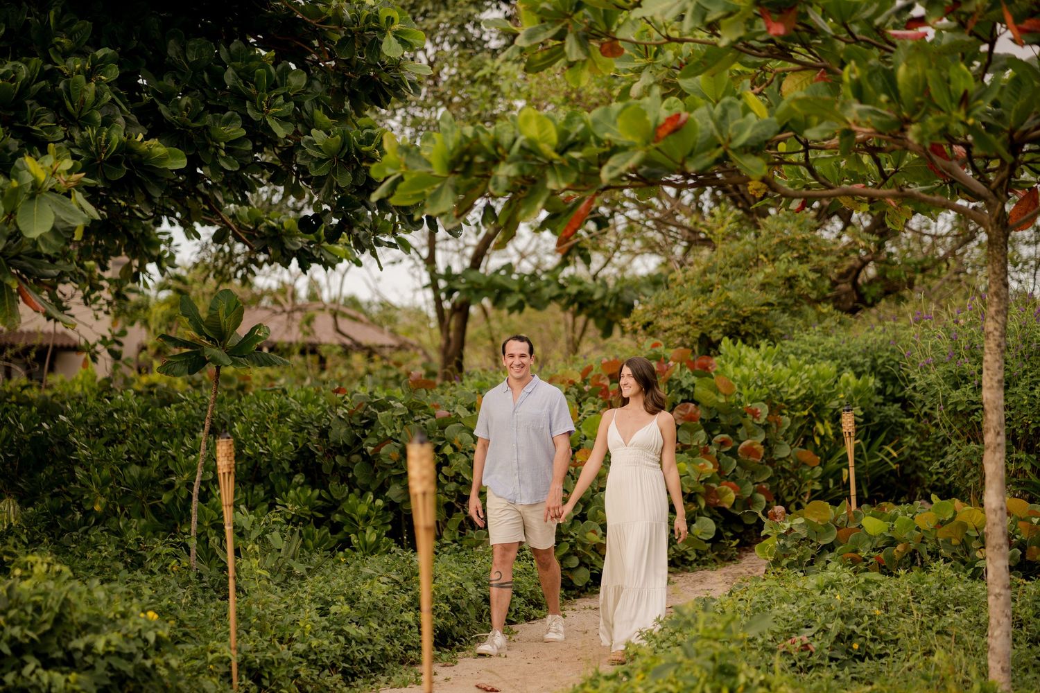Couple walking through lush tropical gardens during a romantic portrait session at Hacienda Pinilla in Guanacaste, Costa Rica.