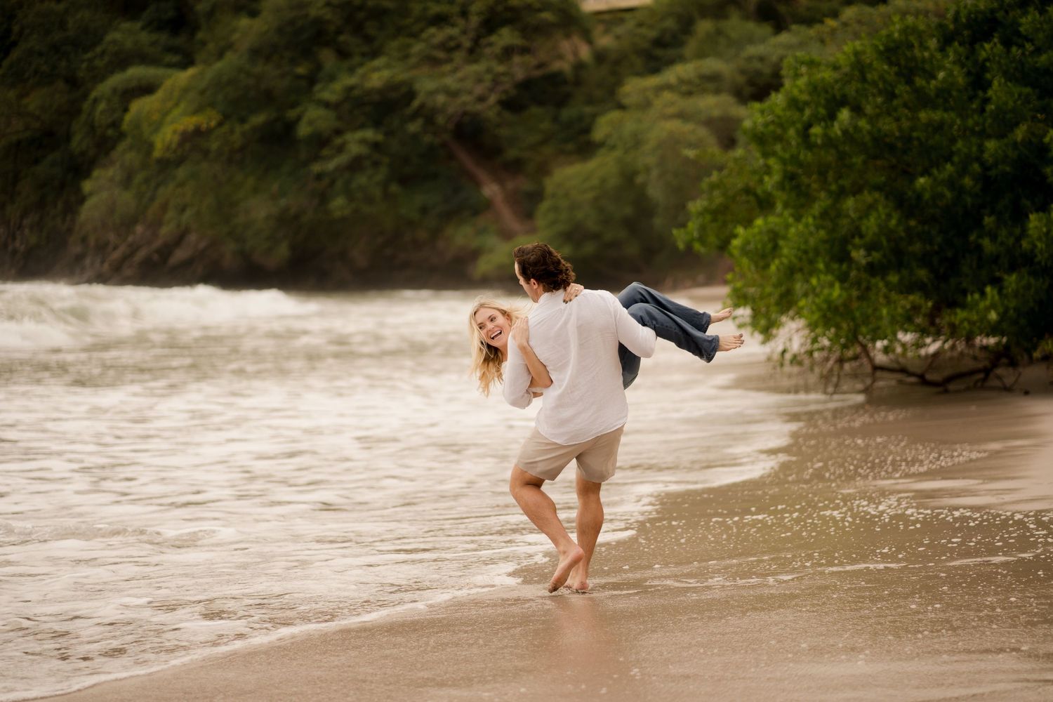 Couple playing by the ocean during a fun engagement photography session at Playa Flamingo in Guanacaste, Costa Rica.
