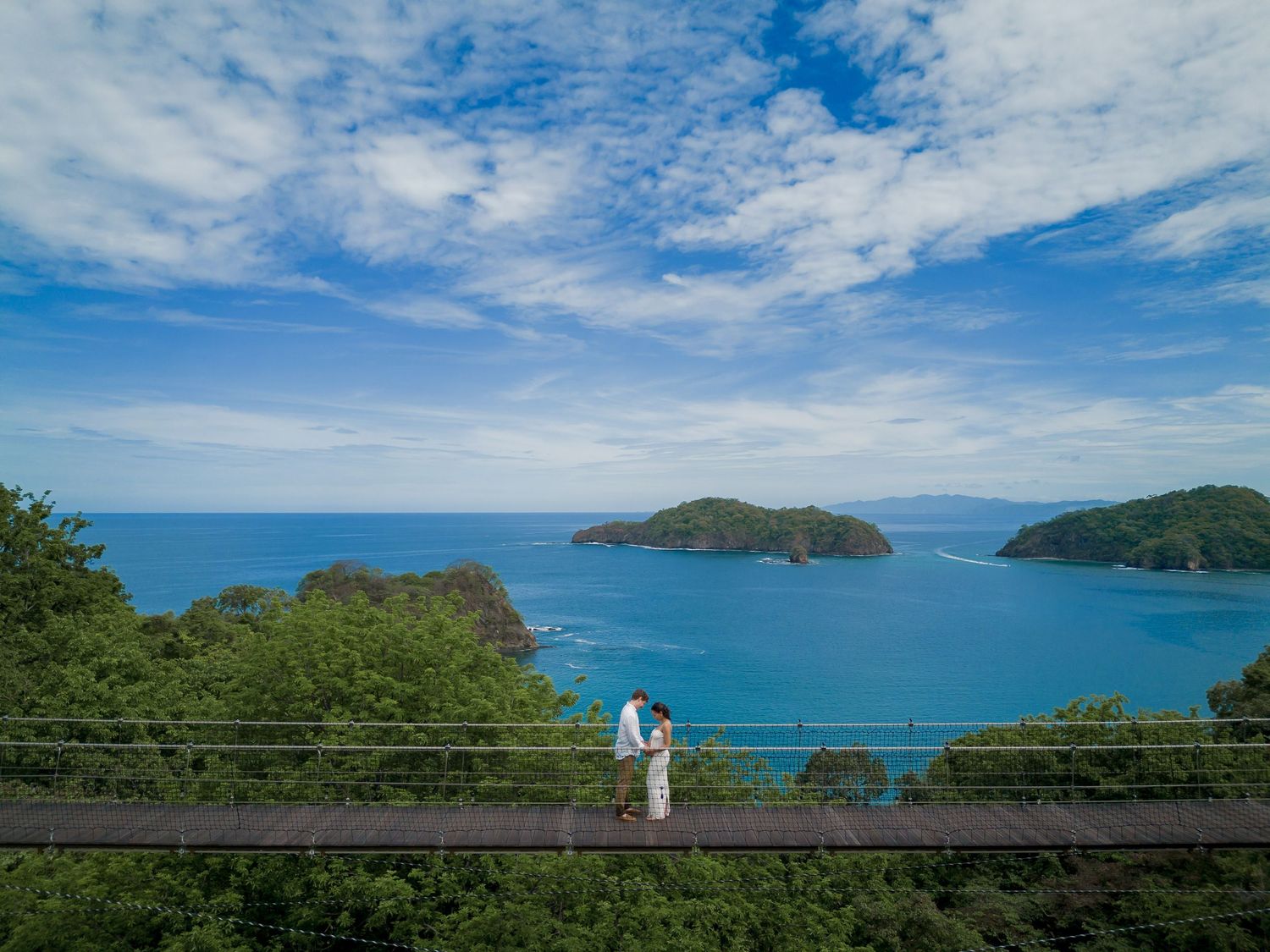 Couple enjoying their babymoon in Nekajui Ritz-Carlton Reserve in Costa Rica on their iconic hanging bridge overviewing to the Pacific Ocean