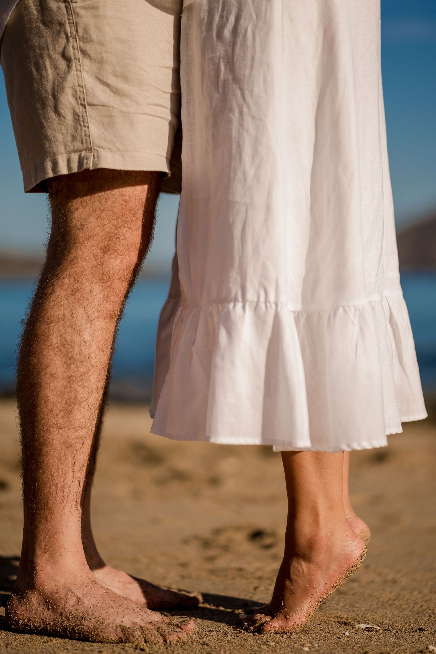 Close-up of a couple standing barefoot together on the beach during an engagement photography session at El Mangroove, Costa Rica.