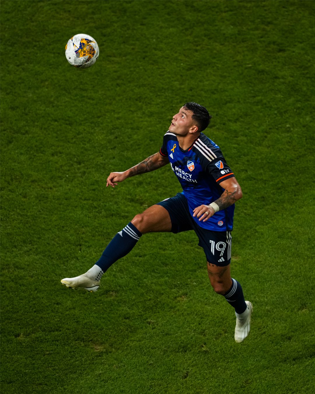 FC Cincinnati player tracks a soccer ball from above while standing on the field.