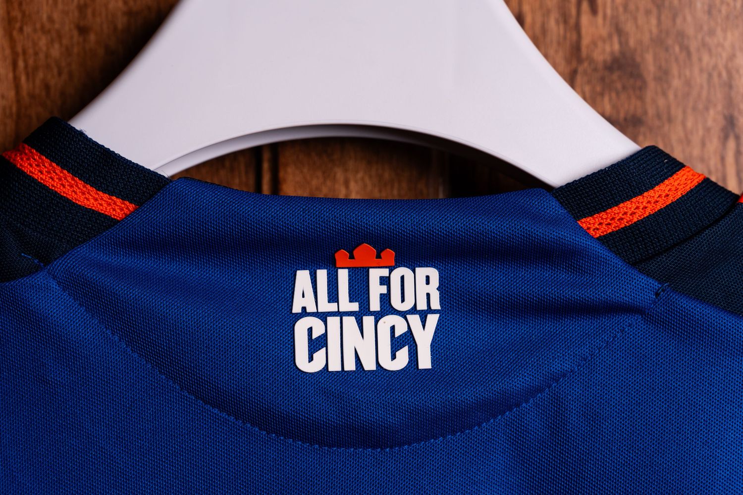 Close-up of the back collar of a blue FC Cincinnati jersey displaying the text “ALL FOR CINCY.”