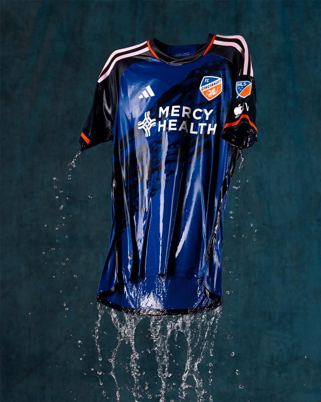 FC Cincinnati jersey suspended against a blue background with water cascading from the garment.