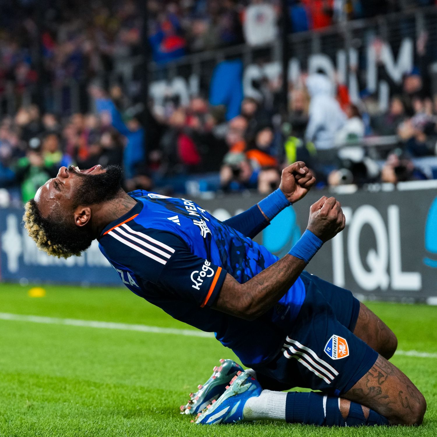 FC Cincinnati player kneels on the field and leans backward in celebration during a soccer match.