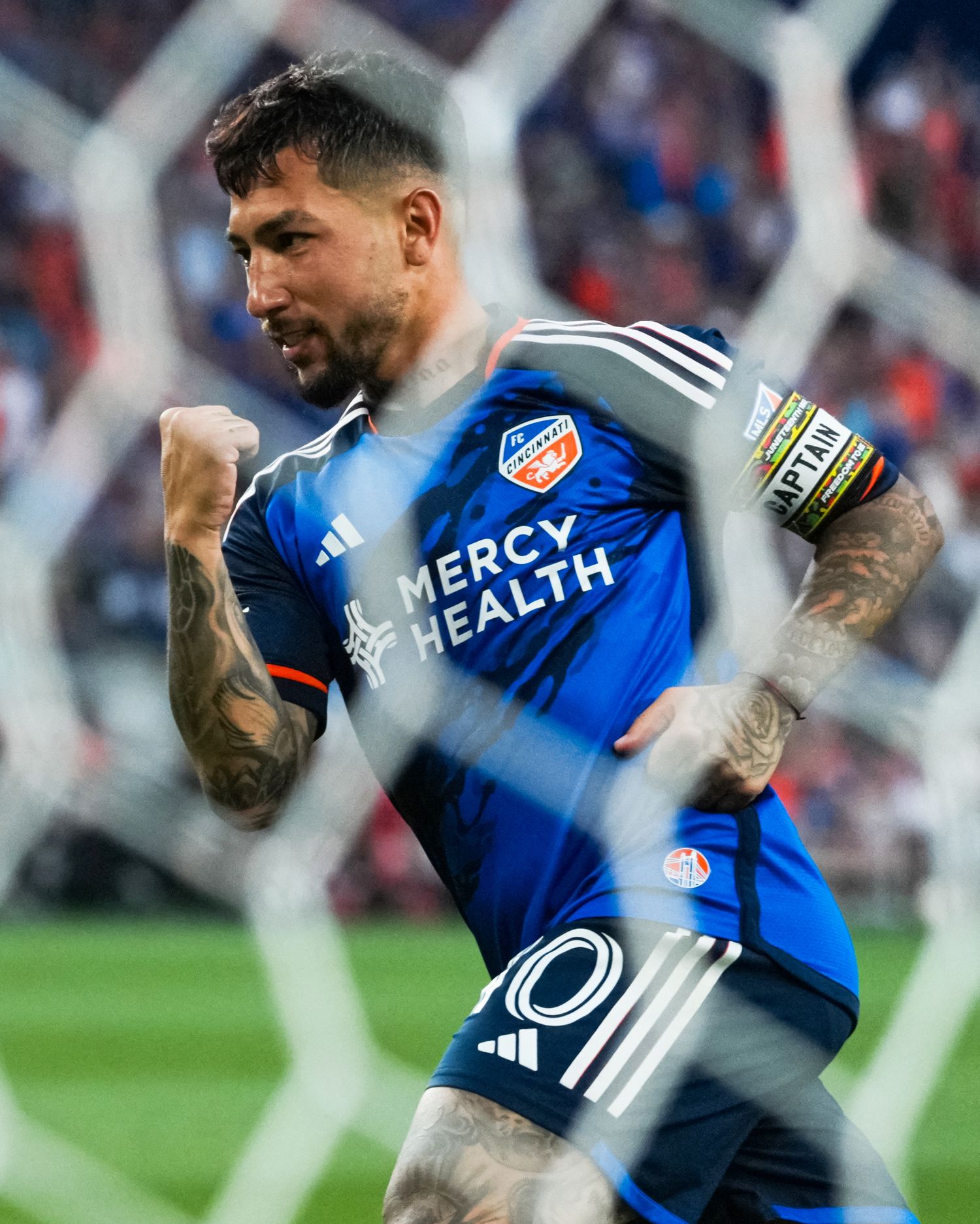 FC Cincinnati player pumps a fist in celebration while viewed through the netting of a goal.