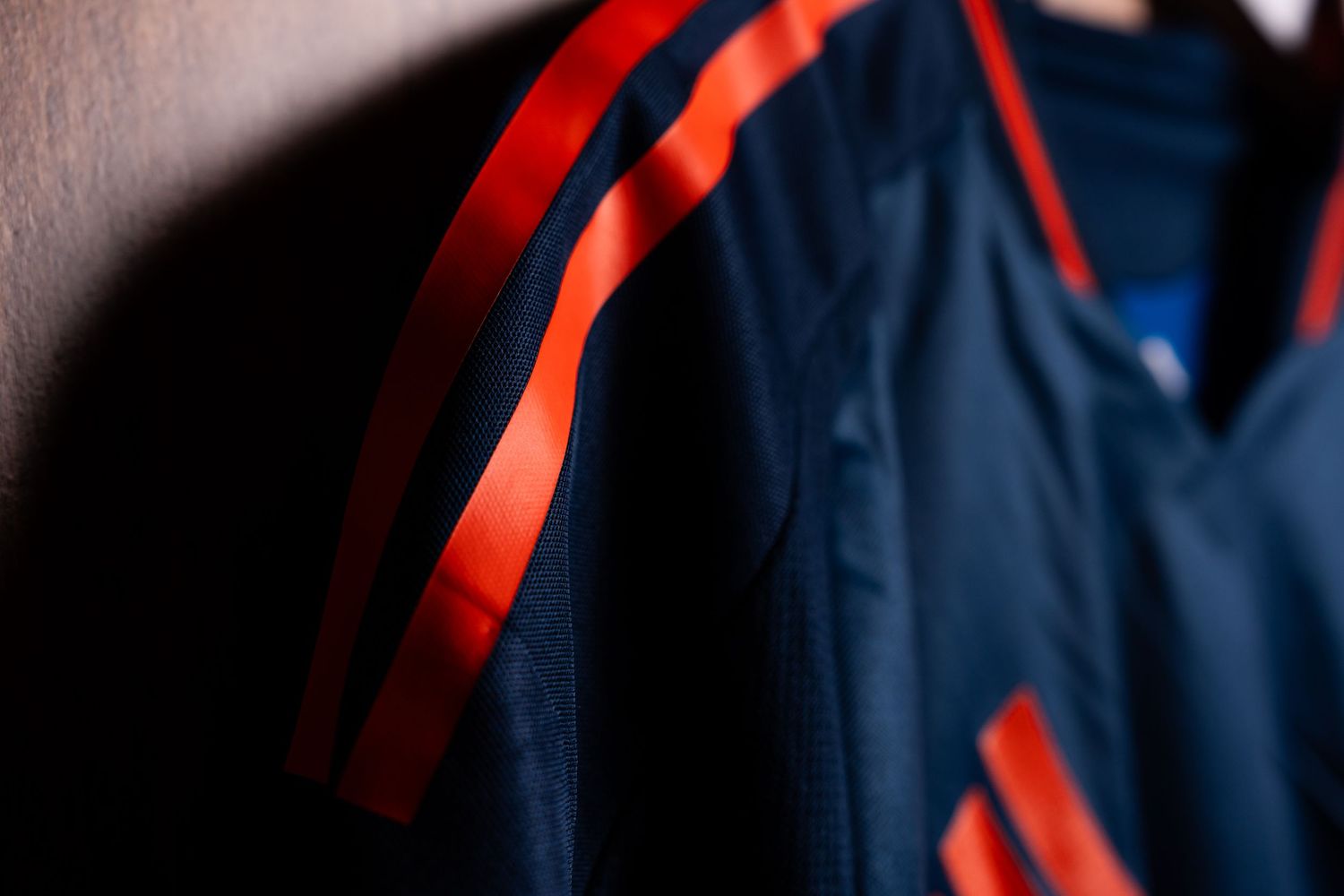 Close-up detail of the shoulder and sleeve of a blue FC Cincinnati jersey featuring bright orange stripes.
