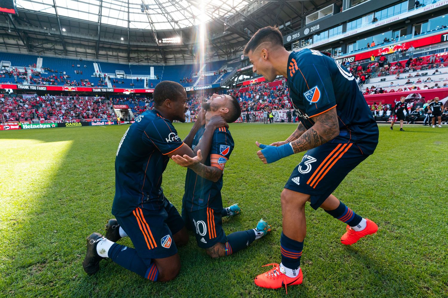 FC Cincinnati players celebrating together on the field inside a soccer stadium.