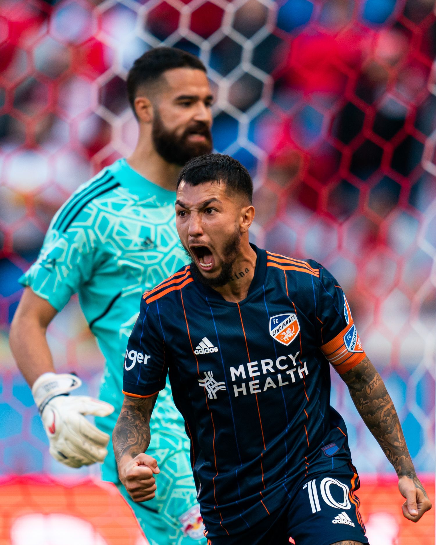 FC Cincinnati player in a navy uniform celebrating near the goal during a soccer match.