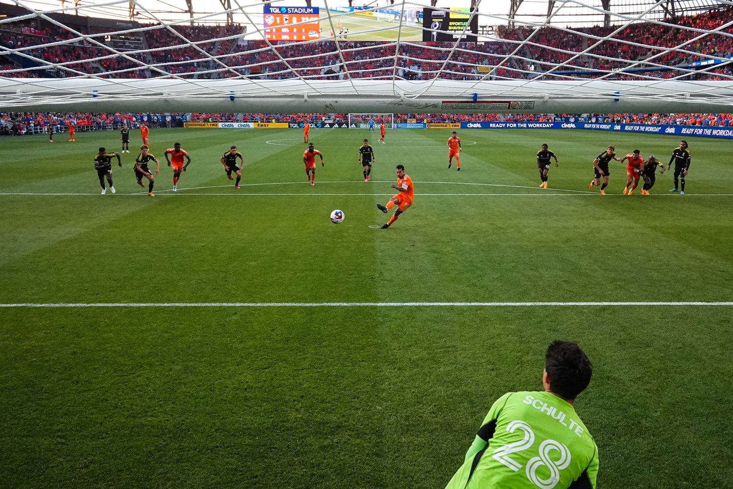 View from behind a goal as a player takes a penalty kick during a soccer match.