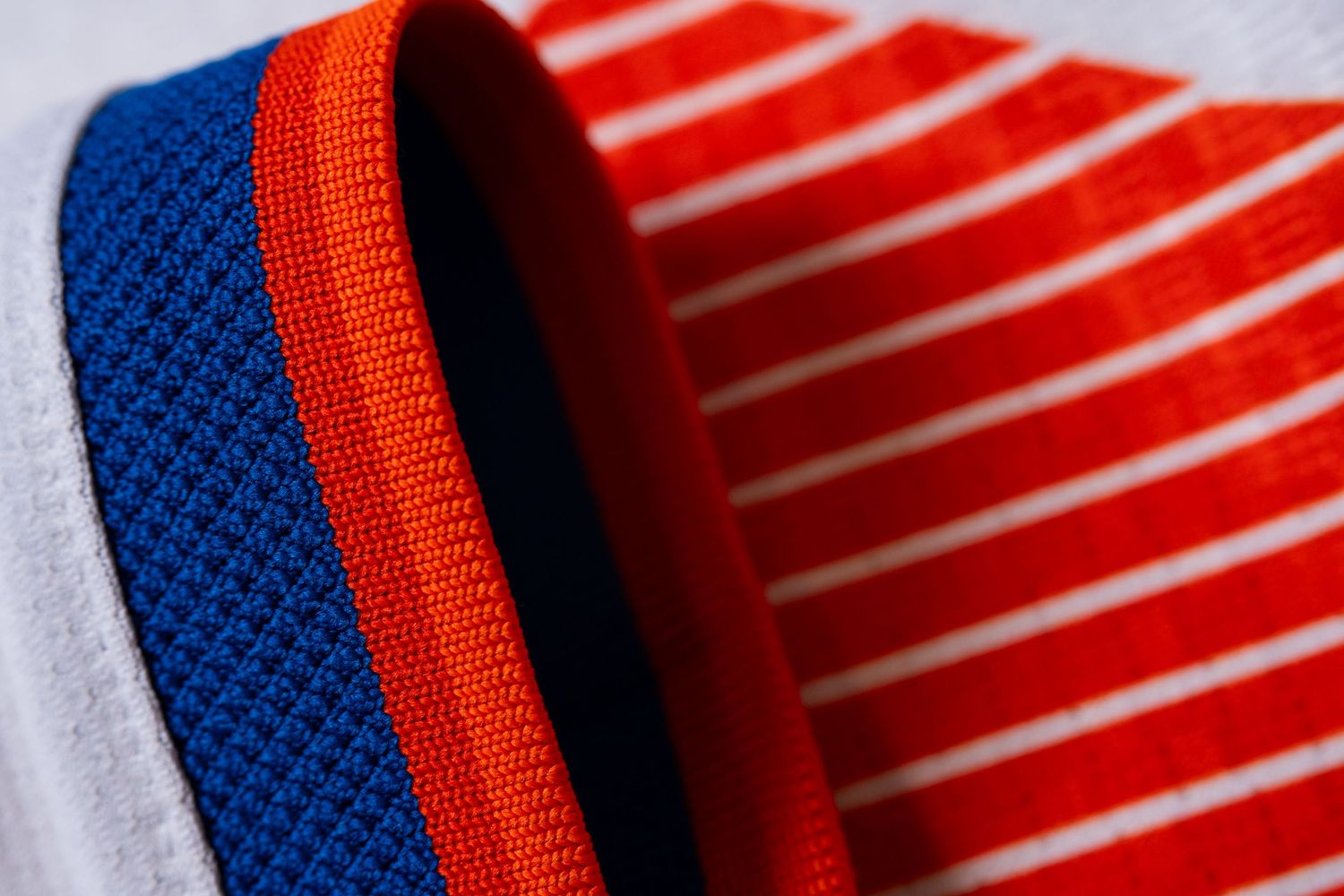 Close-up detail of the blue and orange sleeve and orange graphic pattern on a white FC Cincinnati jersey.