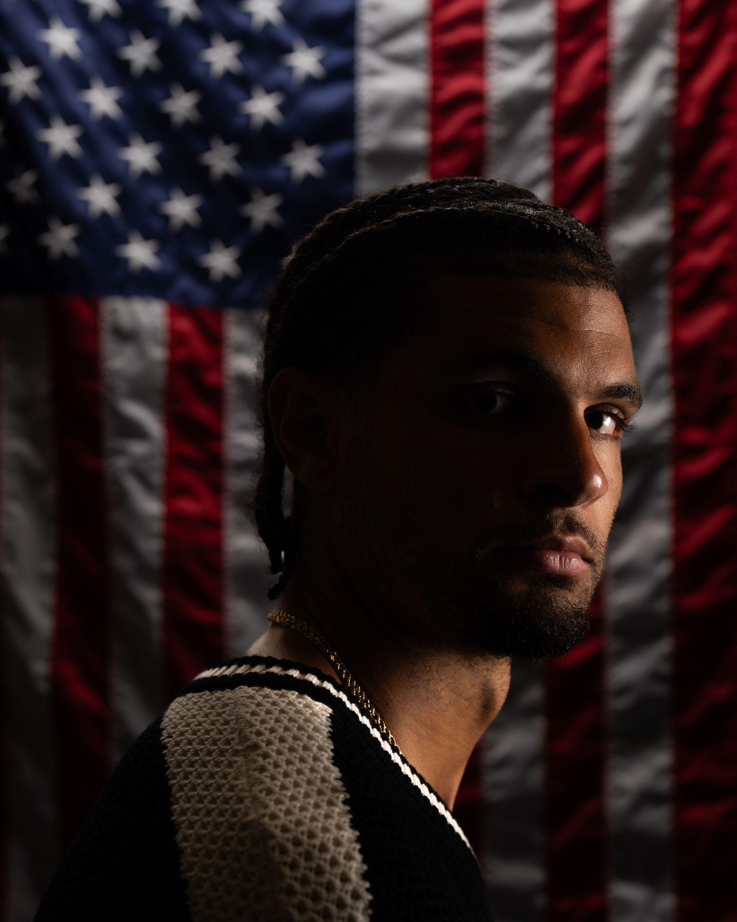 Studio portrait of a person positioned in front of an American flag backdrop.