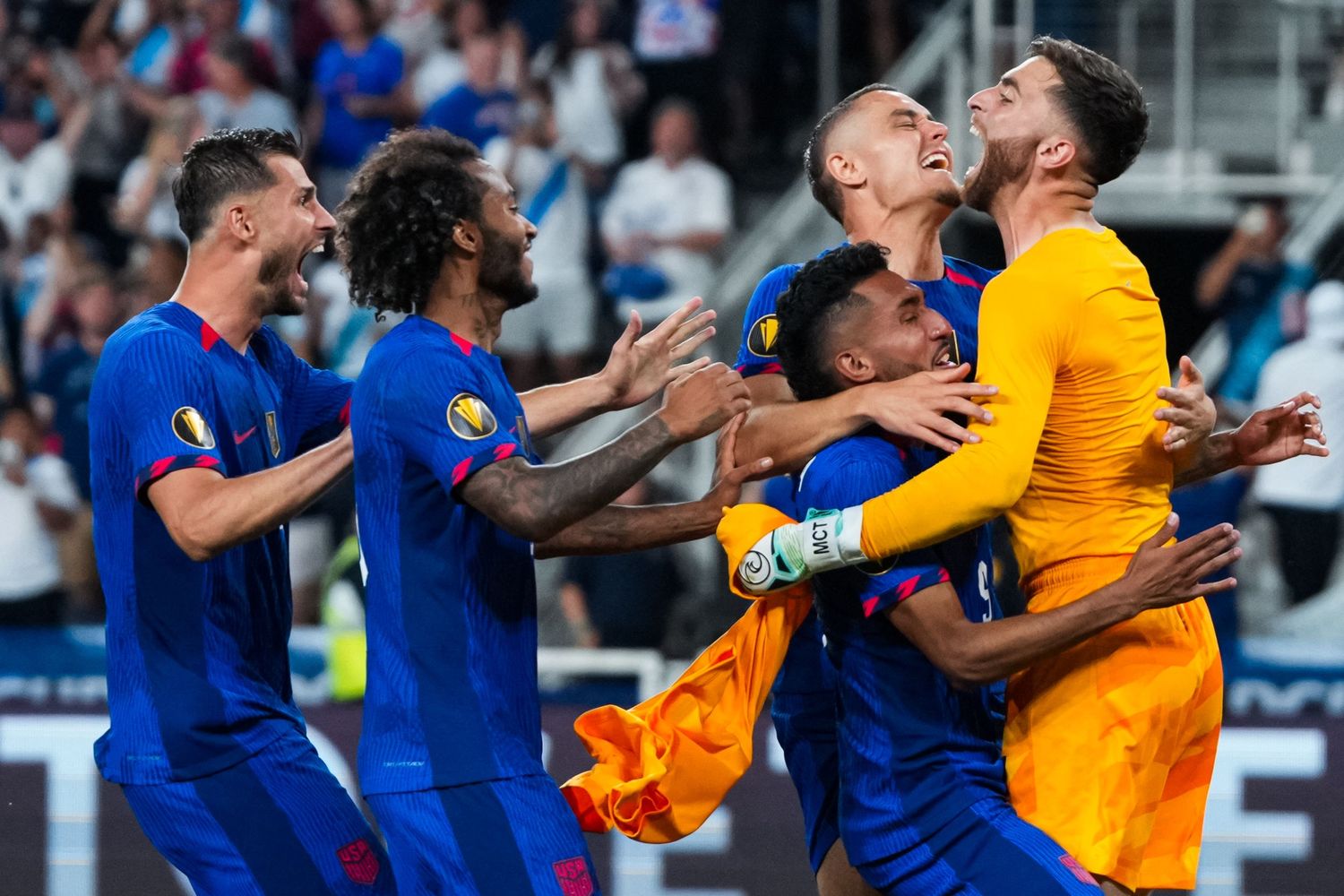 Players in blue uniforms celebrating together following a soccer match.