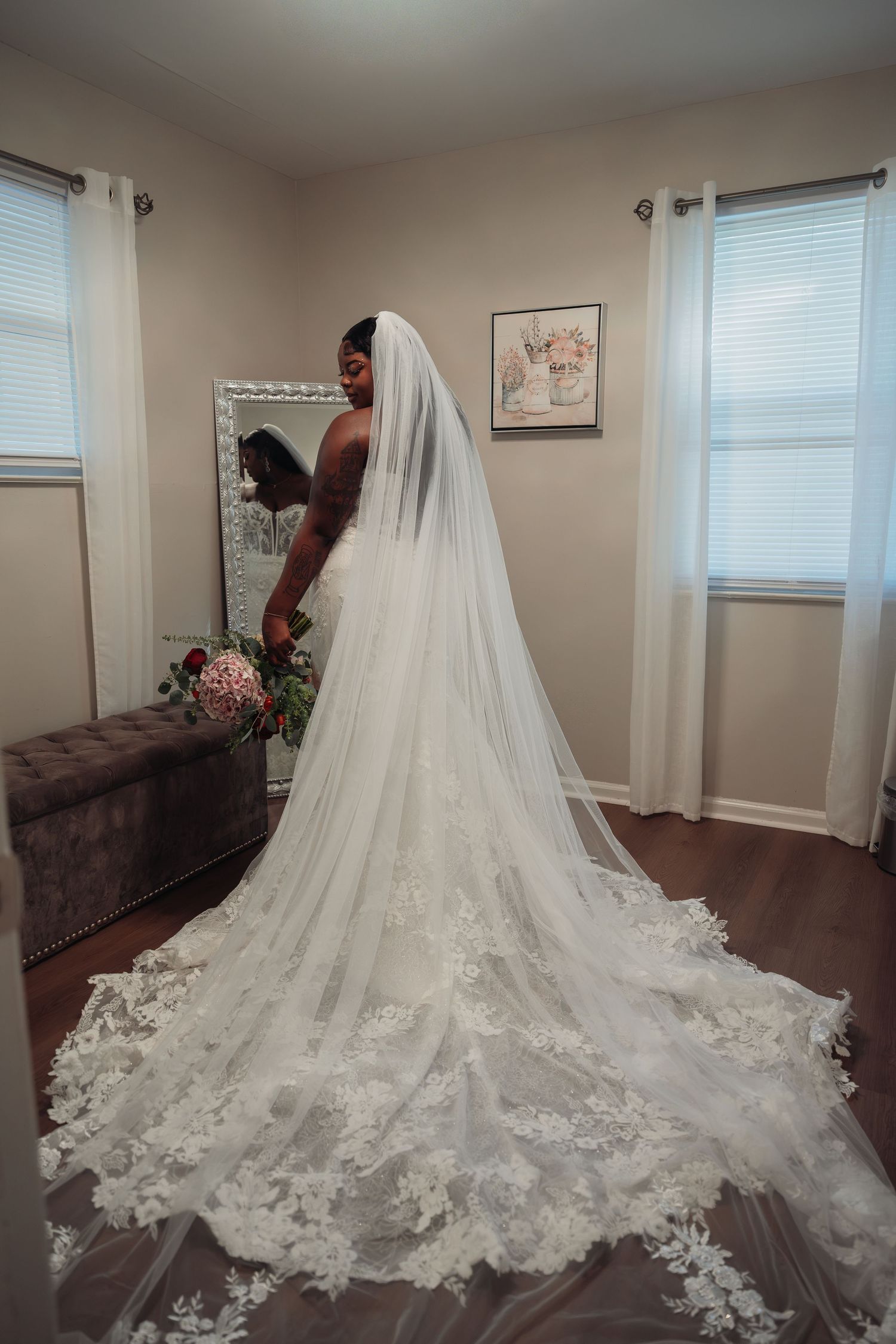 Black bride in elegant lace wedding gown with long cathedral veil viewed from behind.