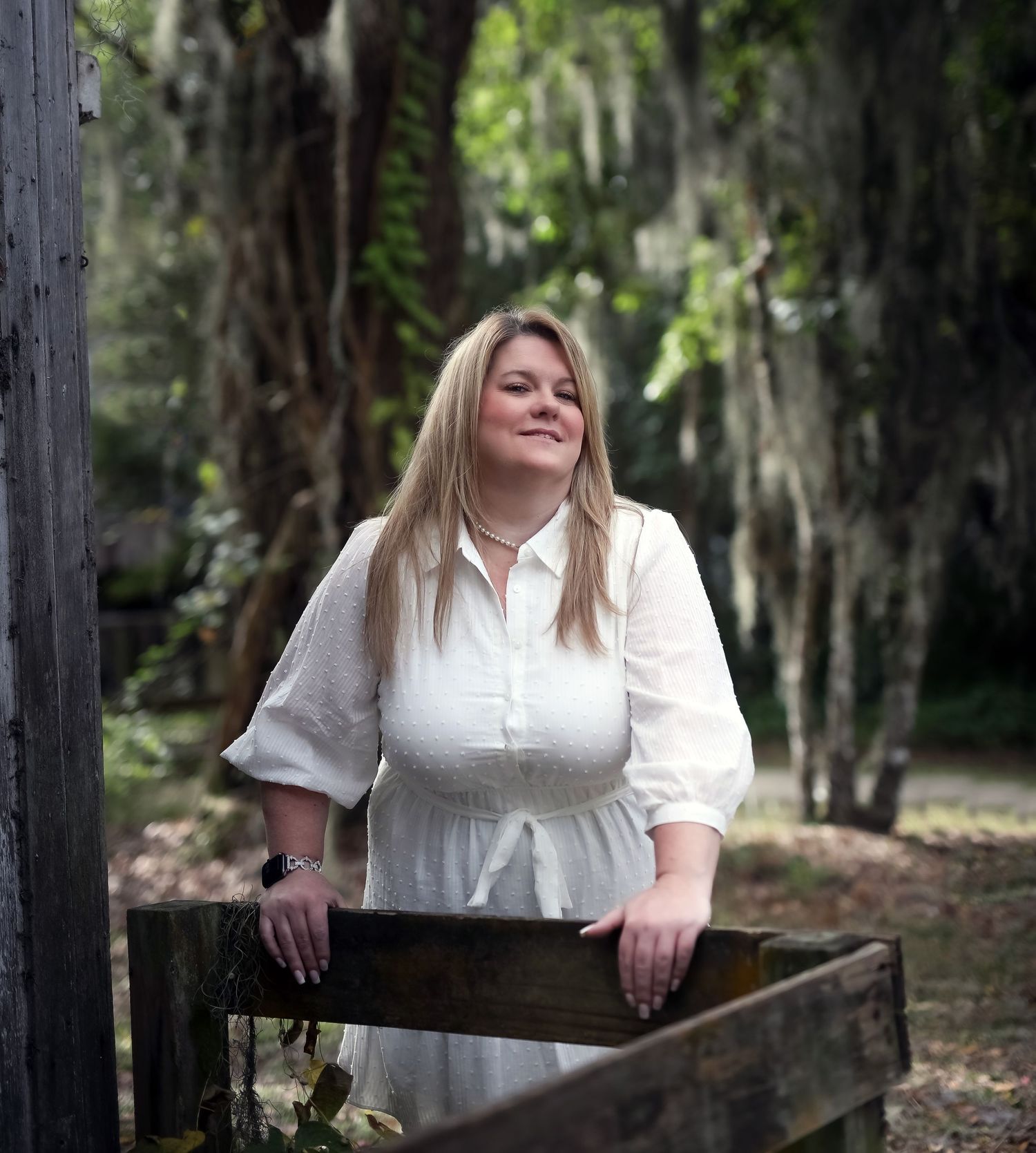 Woman in a white dress standing under moss-draped oak trees, romantic women's portrait