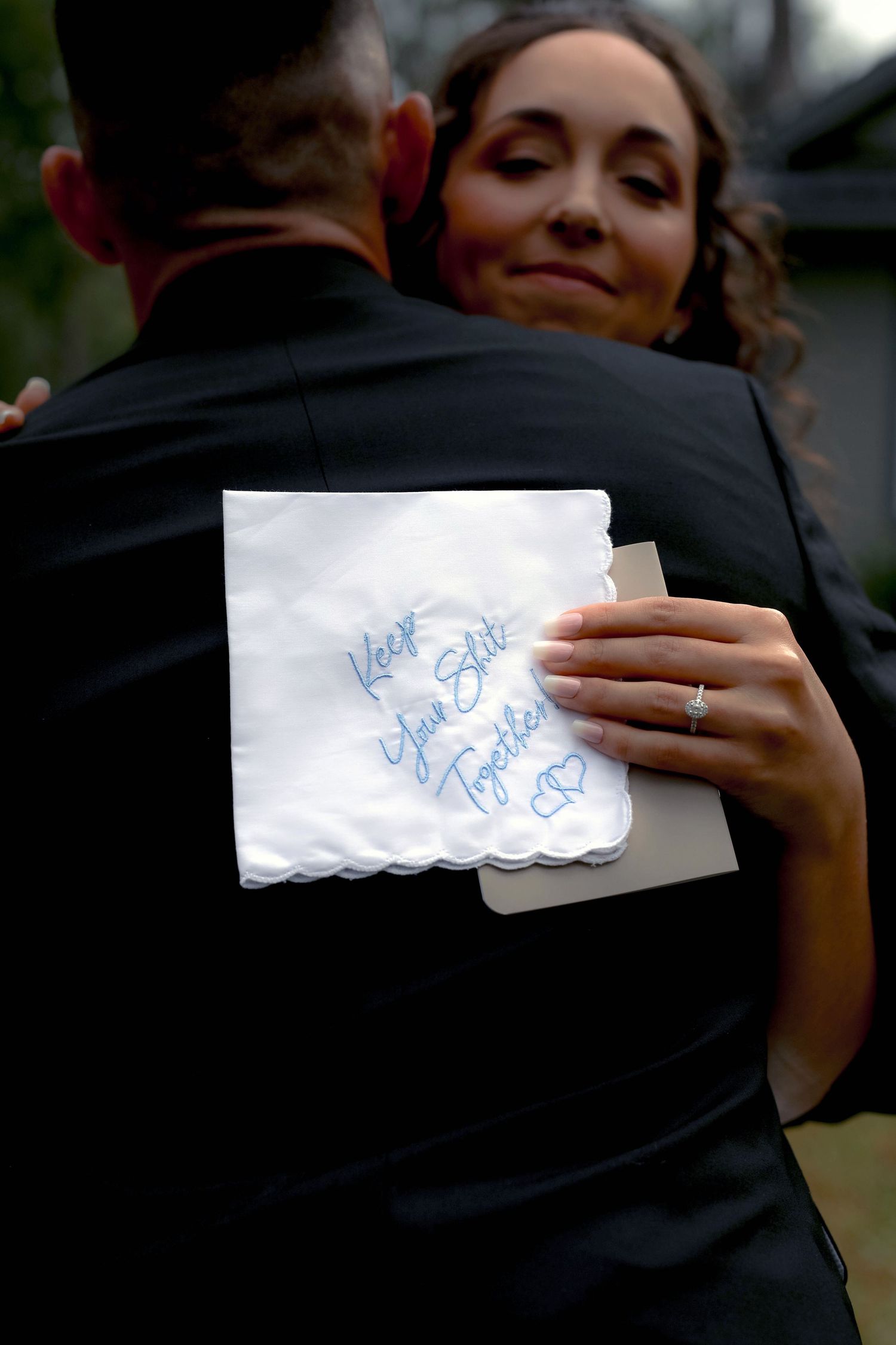 Bride and groom embracing, an embroidered handkerchief reading 