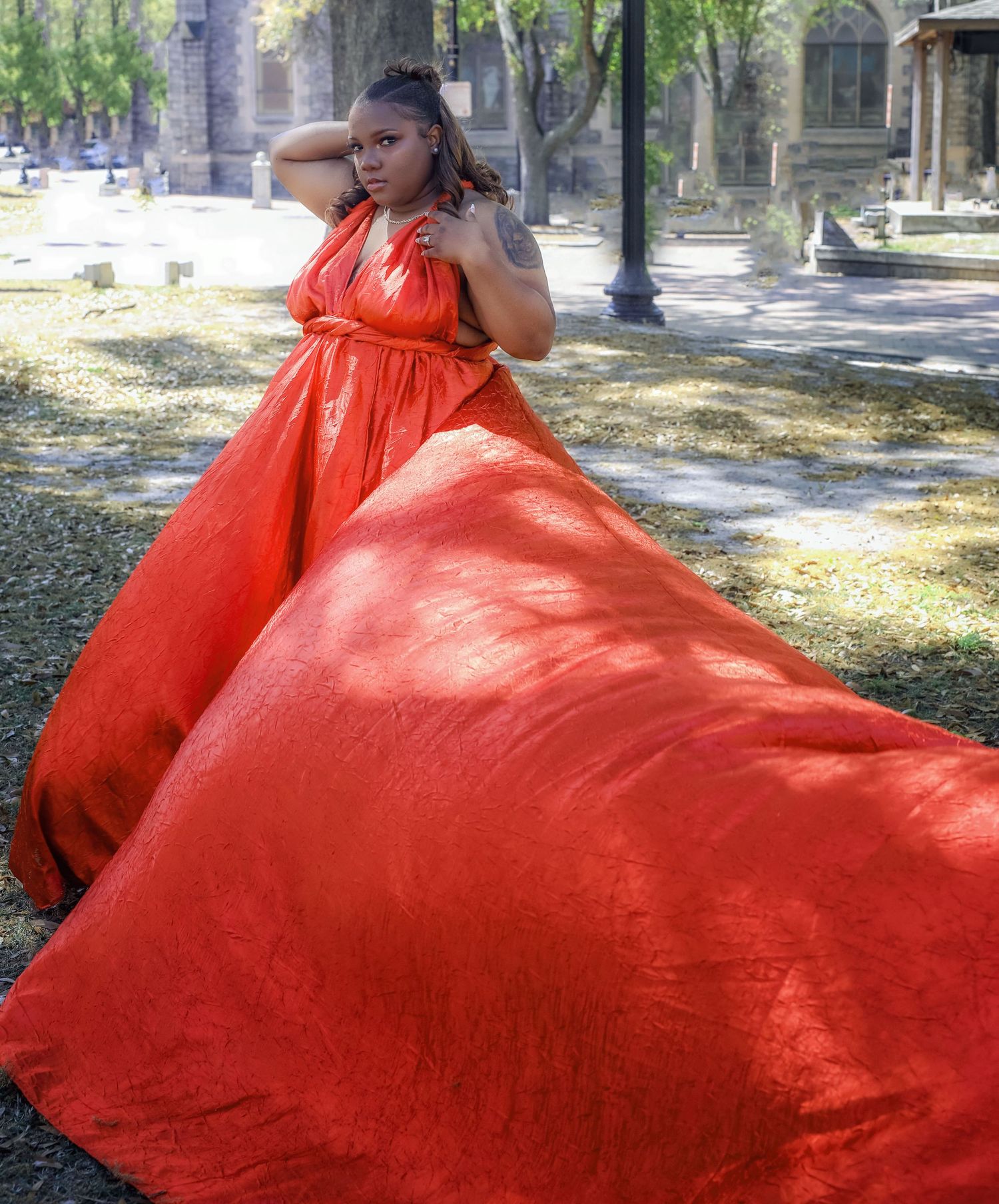Woman in a red flying dress posed in front of a historic downtown stone building