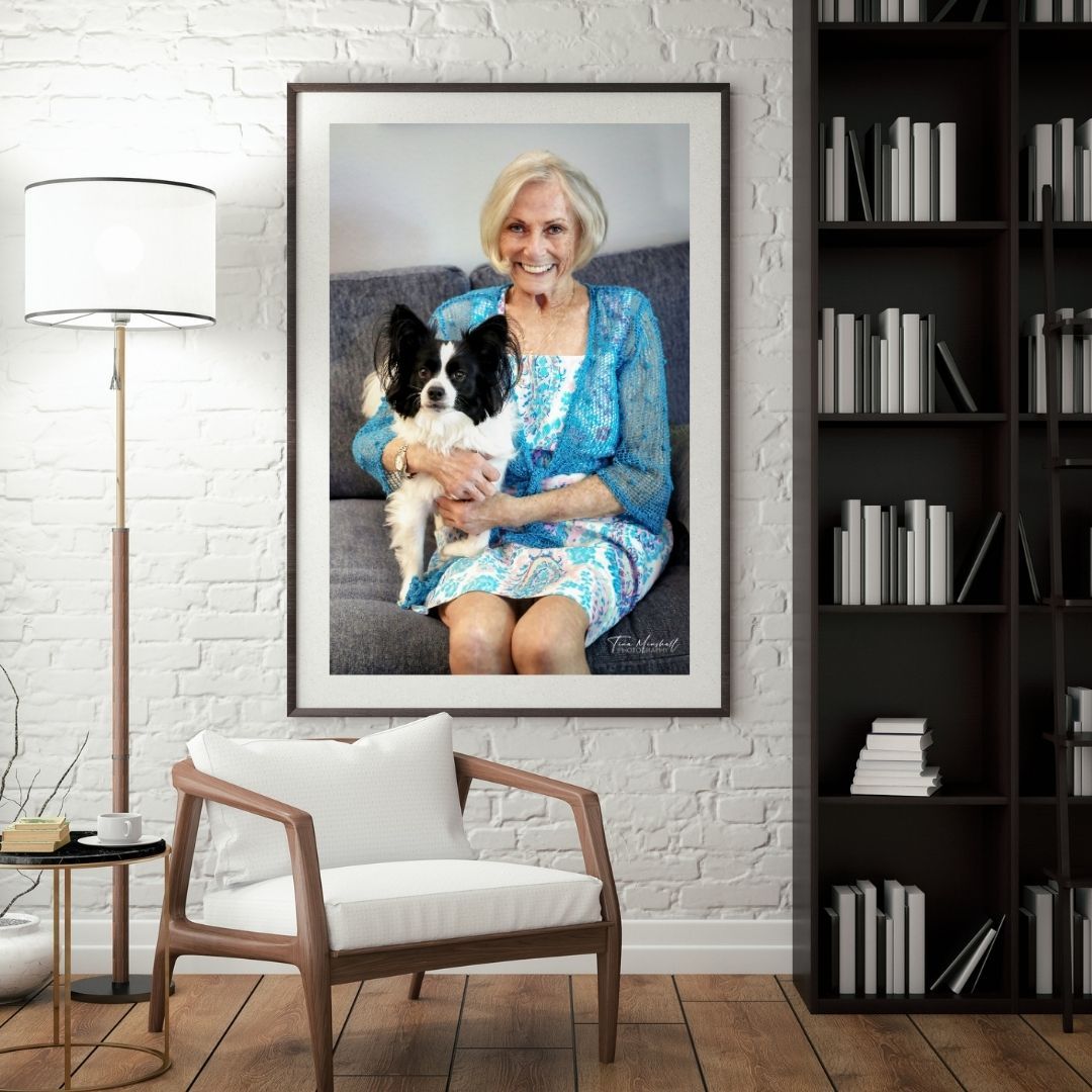 Framed legacy portrait of a smiling older woman holding her small dog on a couch, Jacksonville legacy photography.